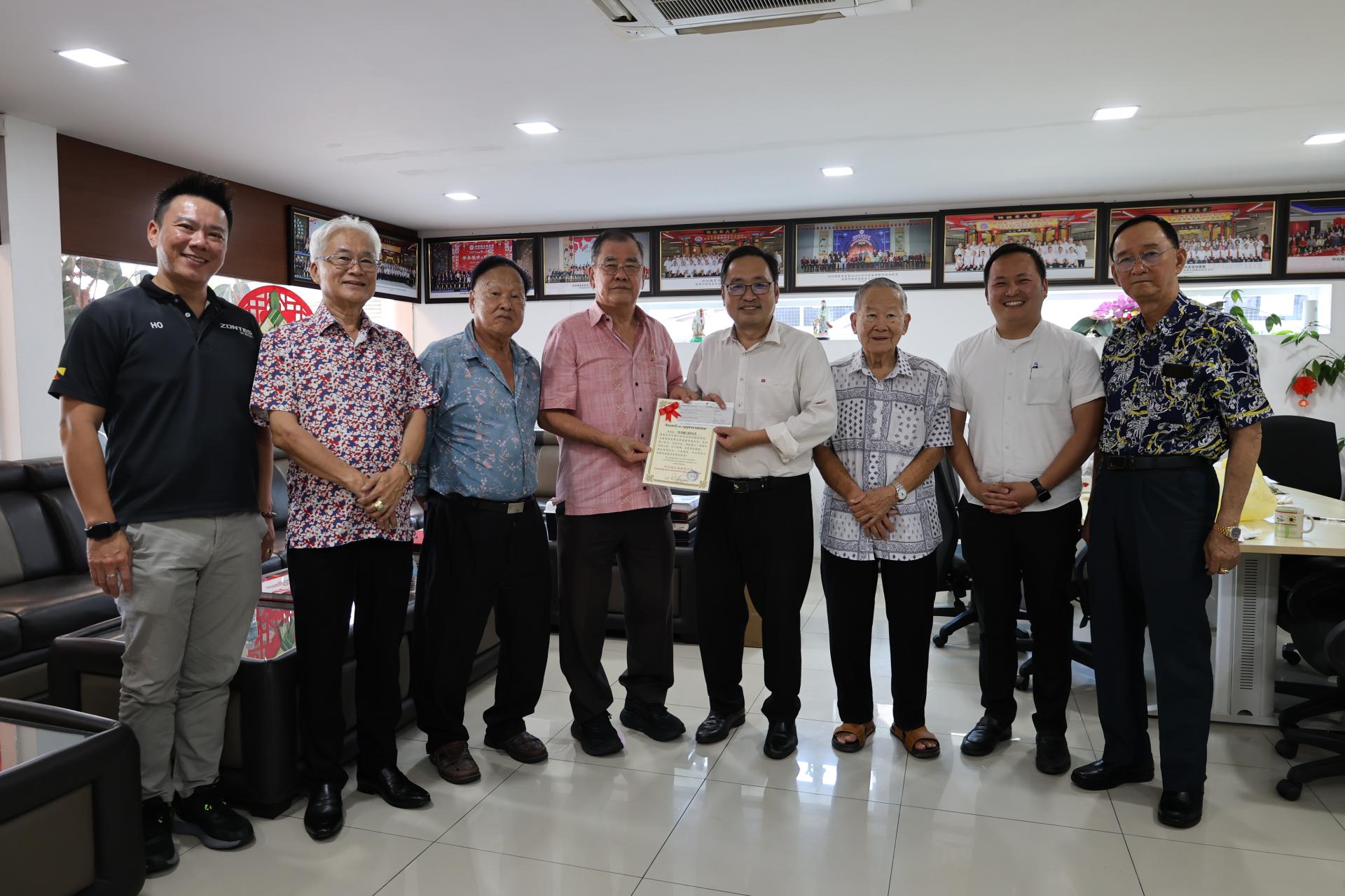 张健仁（右4）在众人的陪同下，移交拨款支票予砂云南善堂主席郑文新（左4）。左起为砂云南善堂青年团团长胡贵祥、福利主任本固鲁田新华、副主席郑瑞福；右起为副主席郭兴开、张健仁特别助理江峰年及副主席钟名宝。