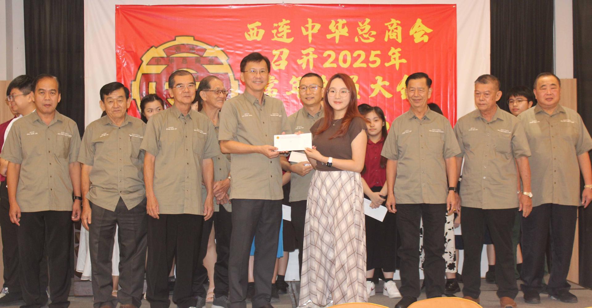 赖招良主持颁发会员子女奖学金予其中一名大学生田家熒时摄。