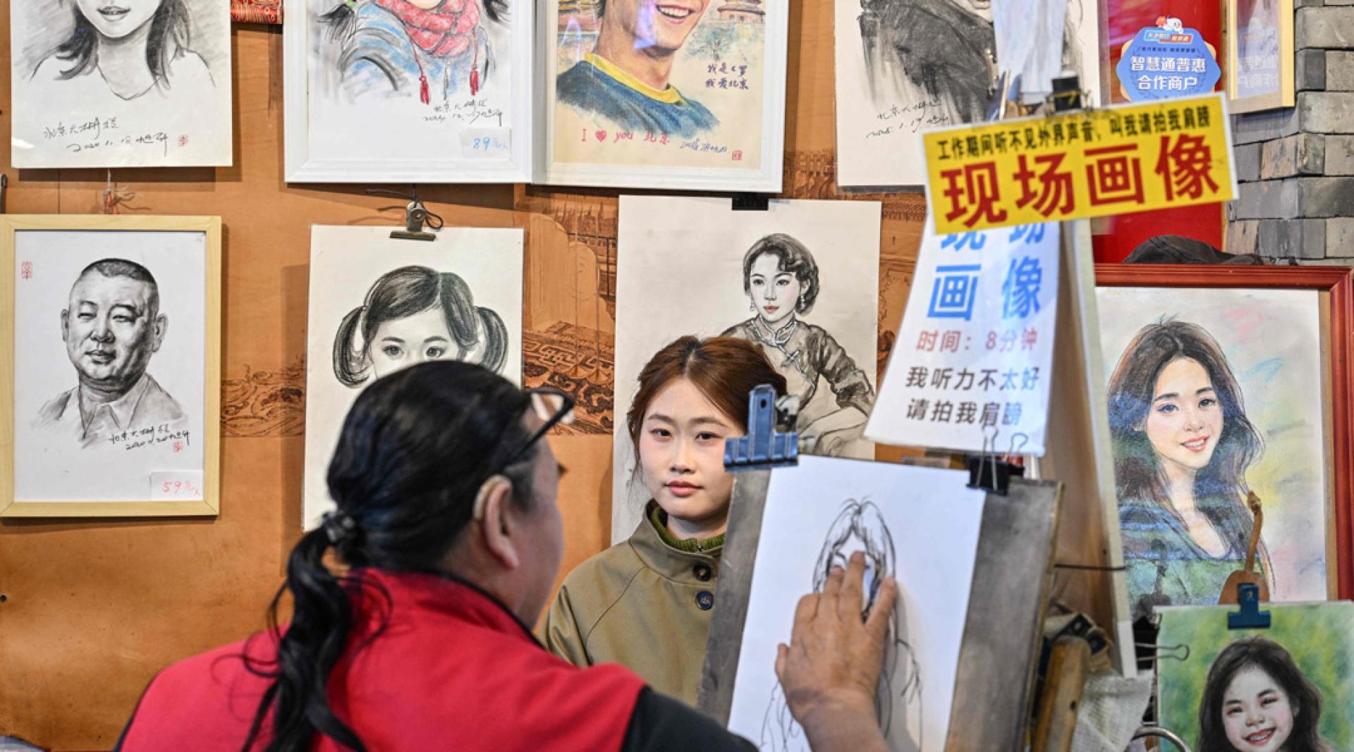 新法明确规定“全面推广普及国家通用语言文字”，也就是普通话和规范汉字。图为画家在北京的市场提供画肖像服务。