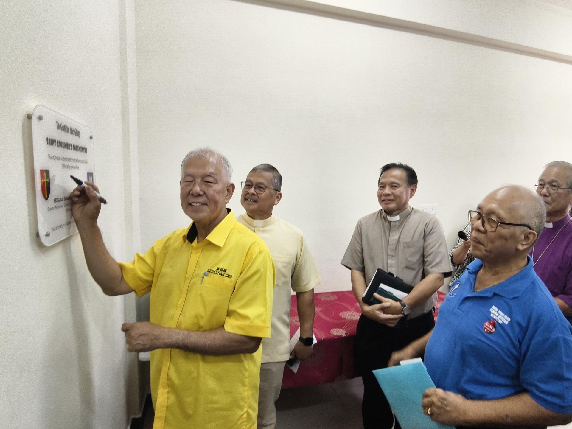 拿督陈超耀在圣哥伦巴堂区关爱事工中心开幕纪念牌匾上签名留念。