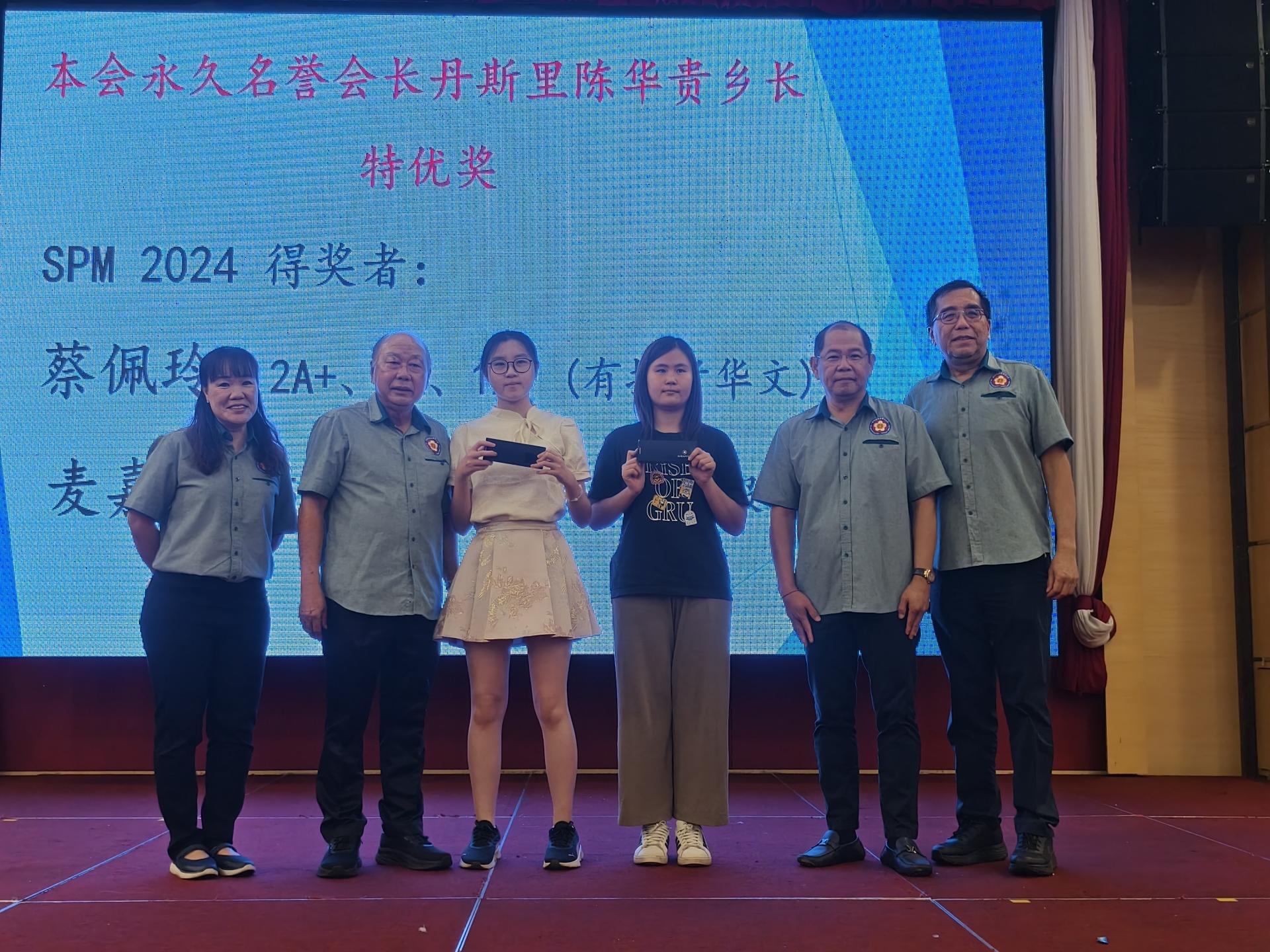 会员子女学业优良奖励金颁发仪式上，颁发美里客家公会名誉会长丹斯里陈华贵特优奖。左起为教育主任蔡田毓、蔡明建、获奖者蔡佩玲、获奖者麦嘉盈、主席江先柱与秘书长杨春德合影。