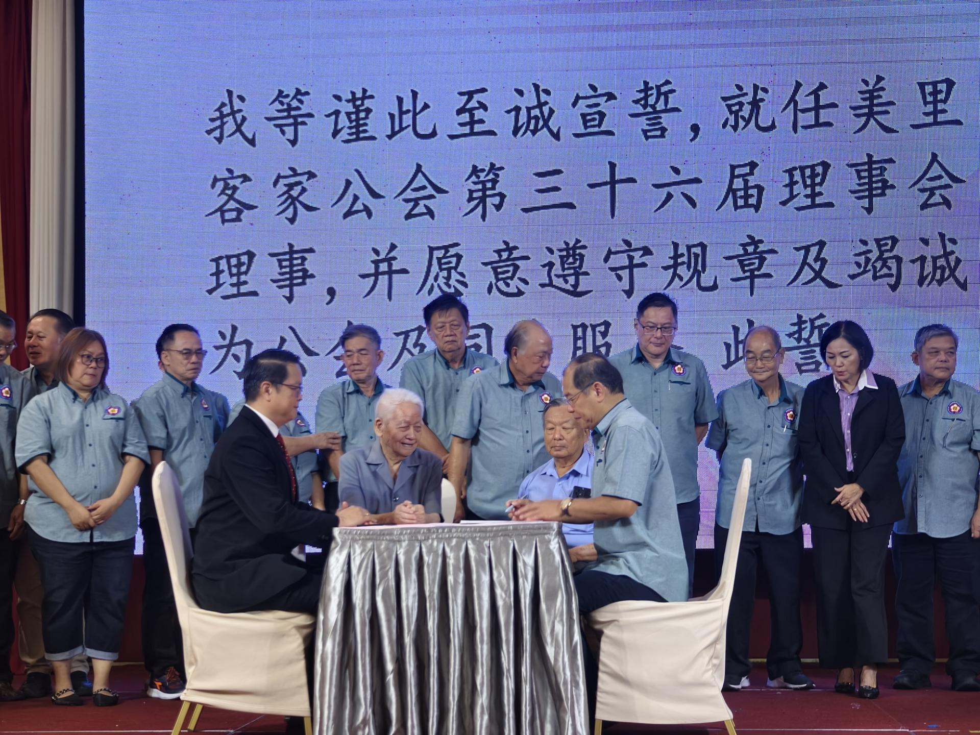 美里客家公会主席江先柱（右）在砂交通部长兼美里客家公会会长拿督斯里李景胜的代表彭小菶（左起）、蔡高船及邓汉祥的见证下，在第36届理事会宣誓书上签名。