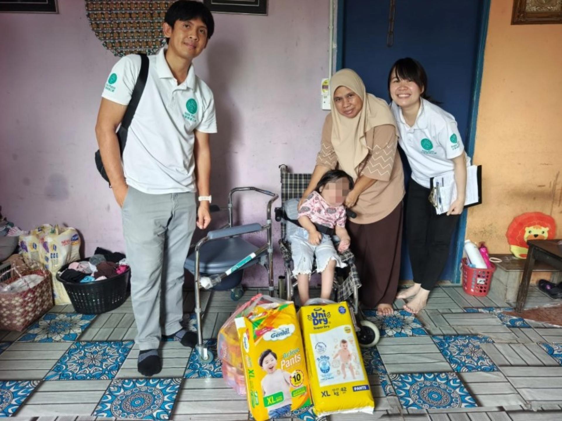 古晋希望之家代表Griffin Deng（左）与Yong Tiong Yieng在Kampung Pasir Pandak向小努莉及其母亲扎莉娅递交援助。