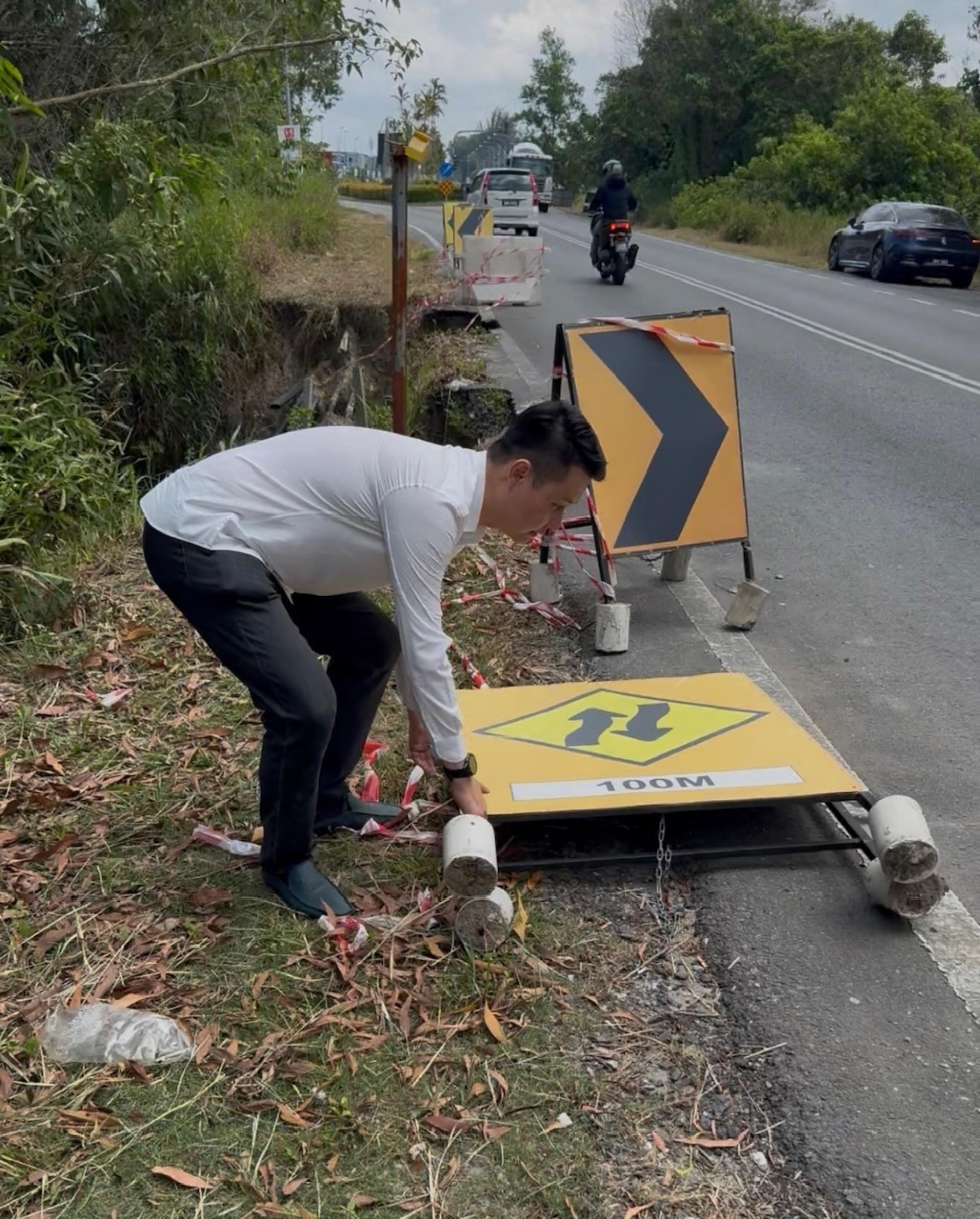 行动党秘书林思健视察时亲自动手把倒下的警示牌抬起重新安置好来，提醒经过该处的往来车辆小心。