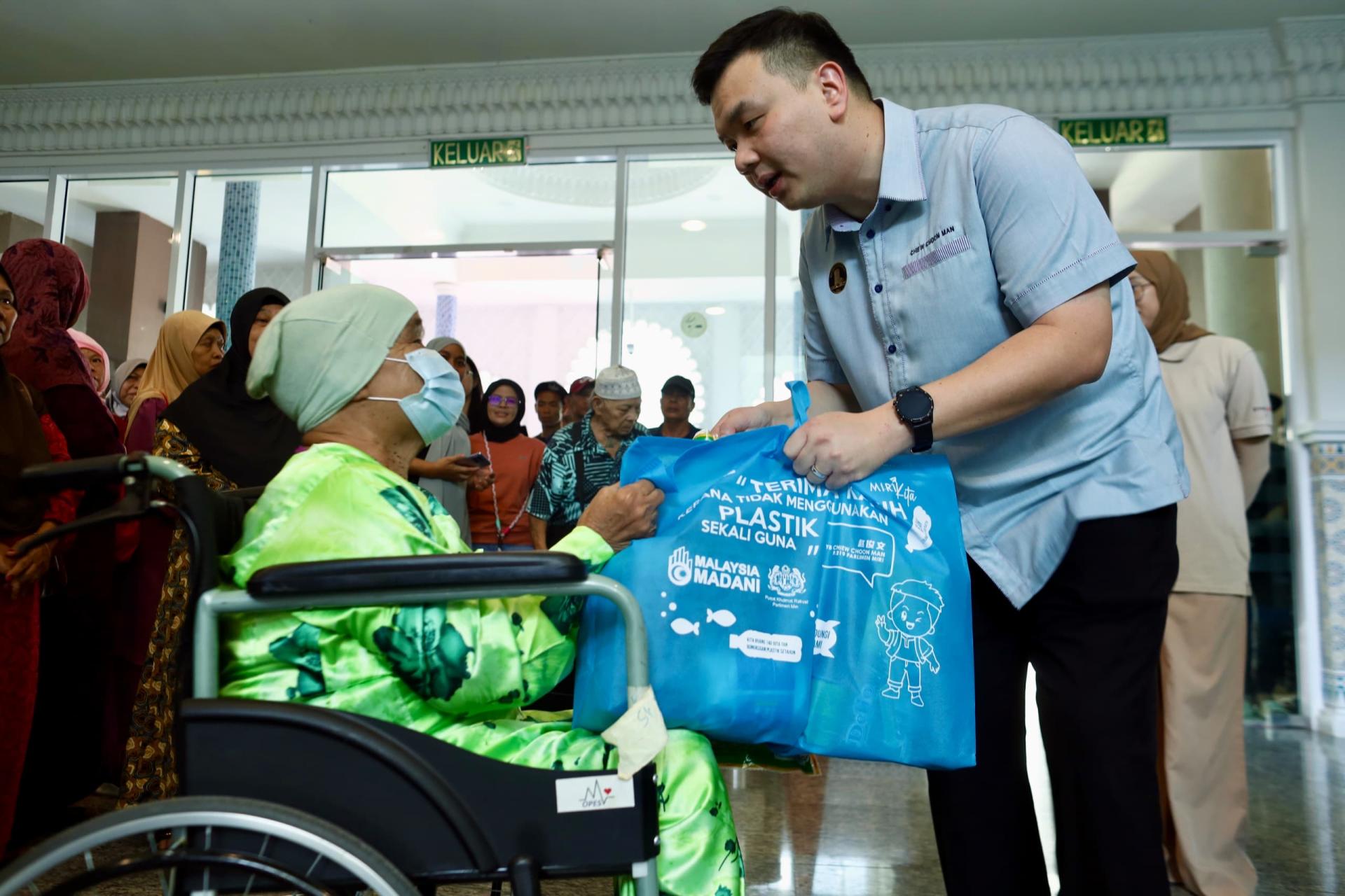 赵俊文派发食品援助予其中一名行动不便受惠者时摄。