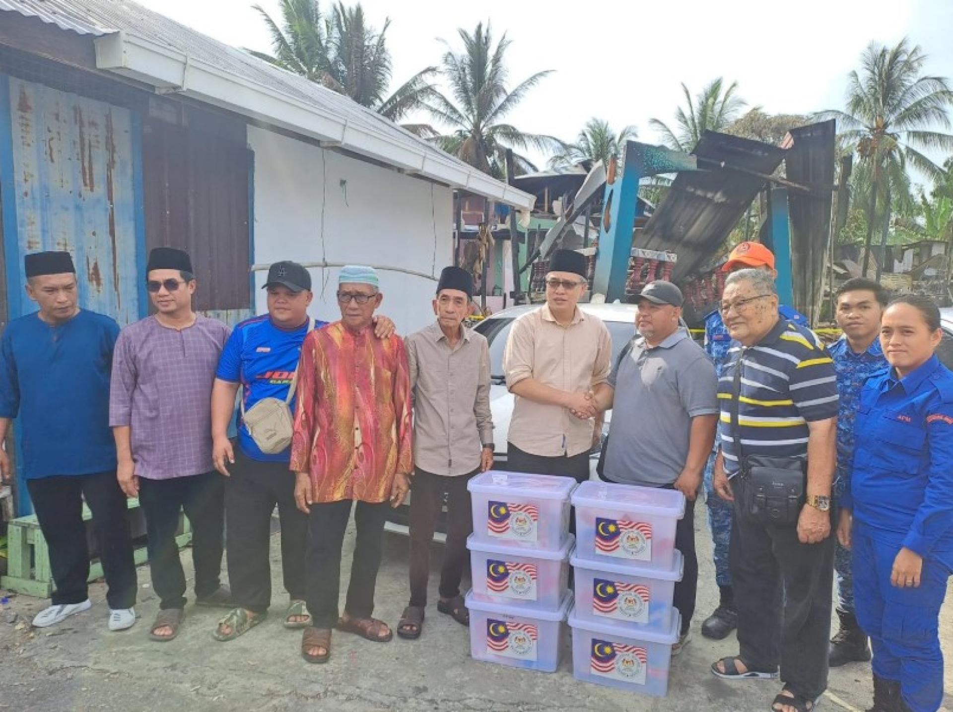 拉西（左6）向其中一名灾民移交援助物资。摄影：UKAS