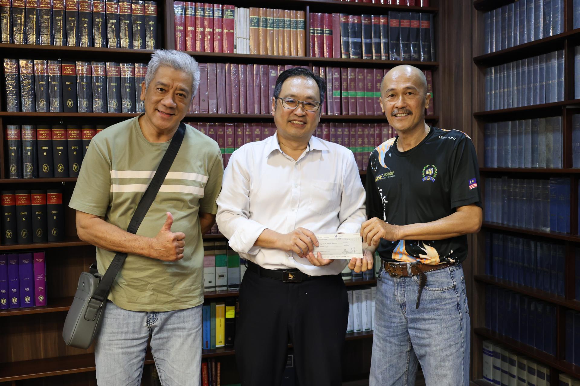 张健仁（中）即席移交拨款支票予邱昌永。左为教练覃懋农。