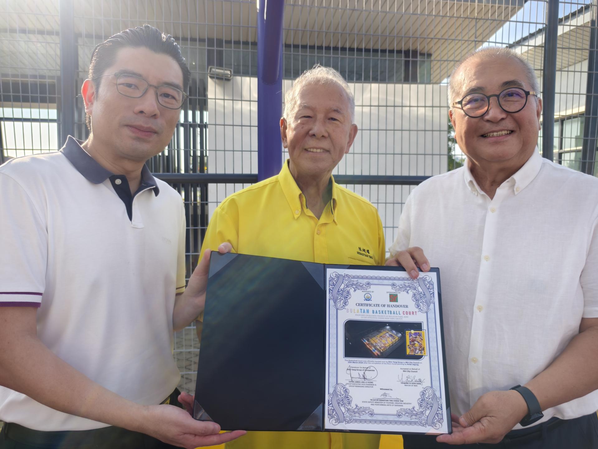 昇阳集团执行副主席兼董事经理拿督林如健（左）在陈超耀见证下，移交篮球场翻新项目证书予俞小珊（右）。