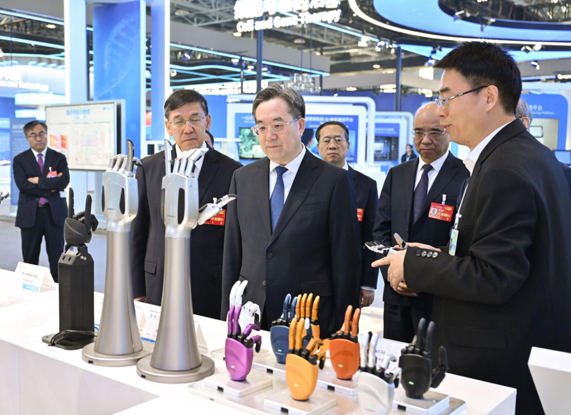 中国国务院副总理丁薛祥（中）出席中关村开幕仪式后，巡视中关村展示中心常设展，并与科技人员进行交流。（图：新华社）