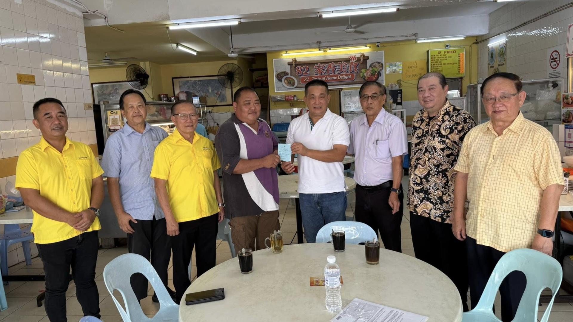 巴都林当区议员施志豪（右4）向弱势申请者（左4）移交砂社会福利局受惠者证明卡。右起至左为施志豪服务团队社区领袖与义工队共同见证：达闽再也商联会名誉会长兼执行顾问林瑞钊、达闽再也商联会会长本固鲁拿督贝朝兴、砂社会福利局资深义工庄城德、本固鲁严安干、资深义工詹兴民及陈义华。