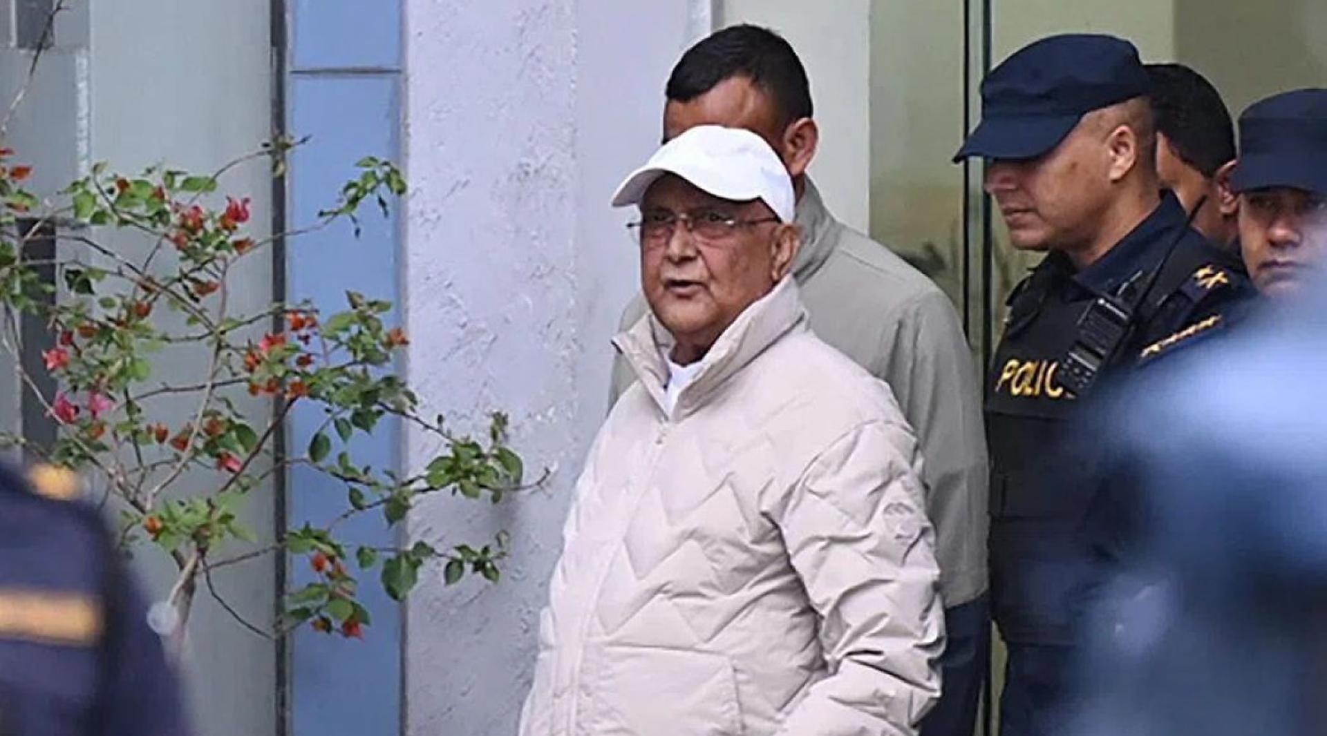 3月28日，尼泊尔前总理奥利（白色鸭舌帽）离开加德满都地区警察局，被警方押送至医院。