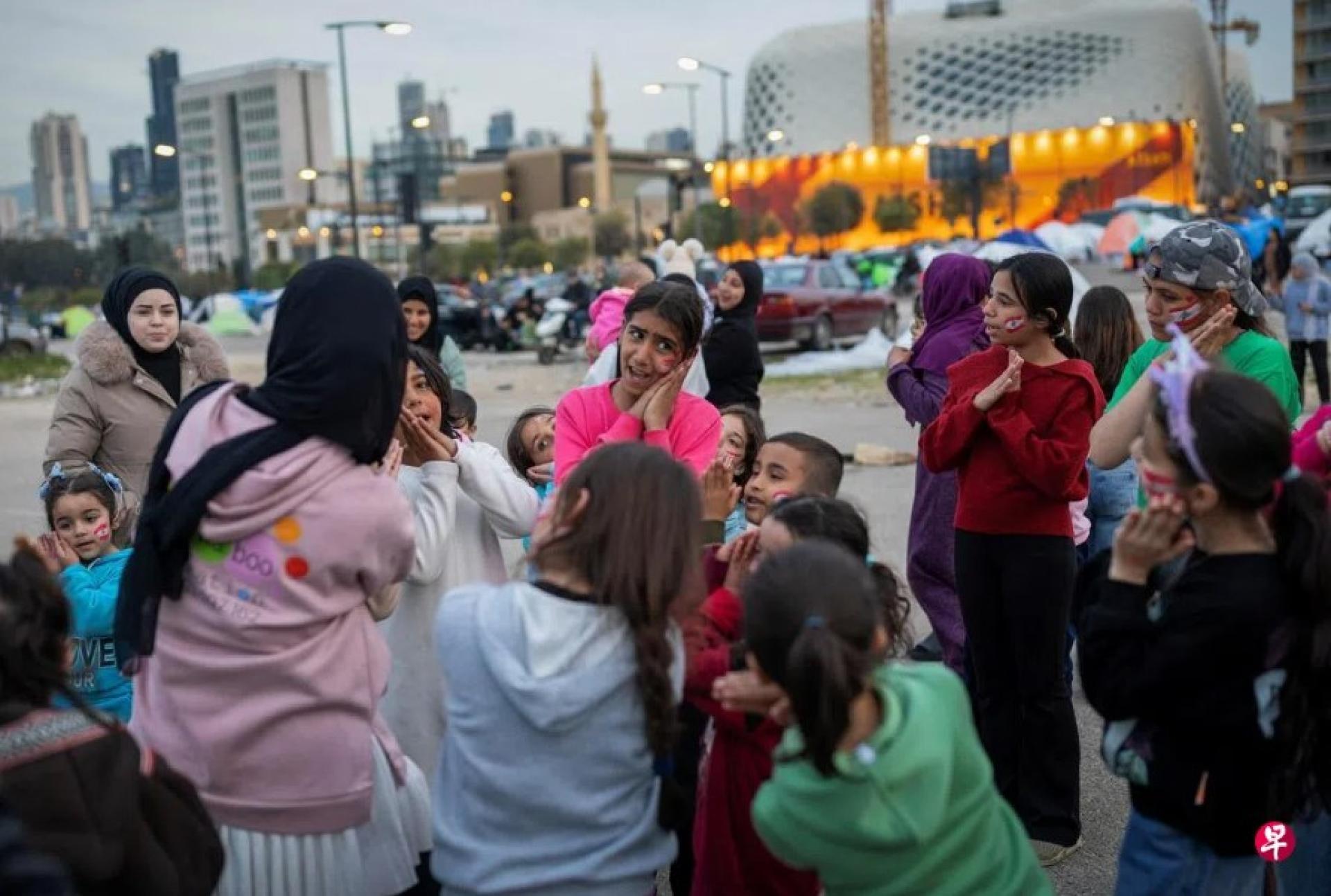 3月28日，在黎巴嫩贝鲁特，一名志愿者在临时安置流离失所者的营地里为孩子们唱歌。