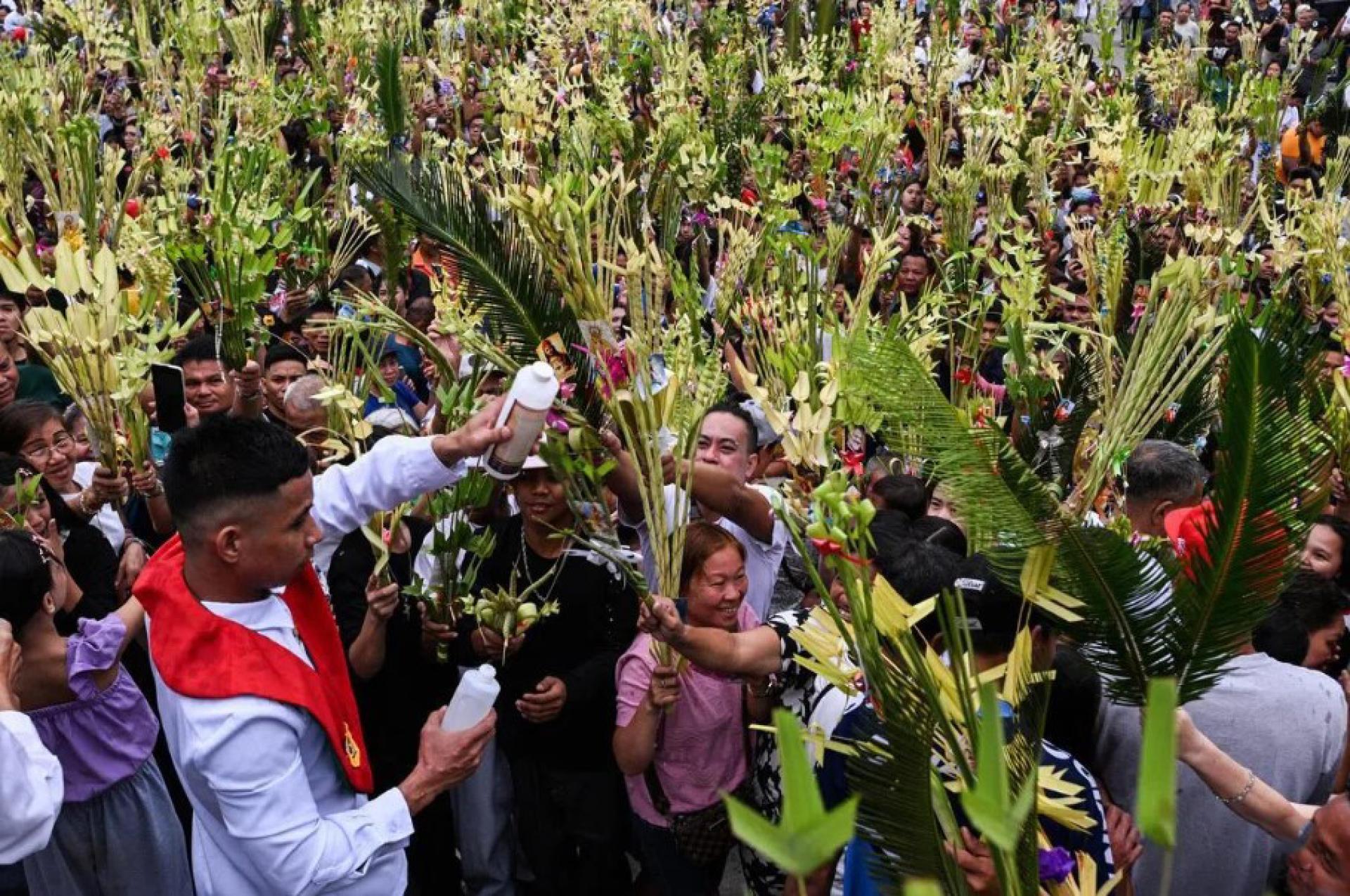 菲律宾天主教徒在首都马尼拉以北布拉干省（Bulacan）的露德圣母岩洞圣殿参加棕枝主日庆祝活动，接受神父的洒圣水祝福。