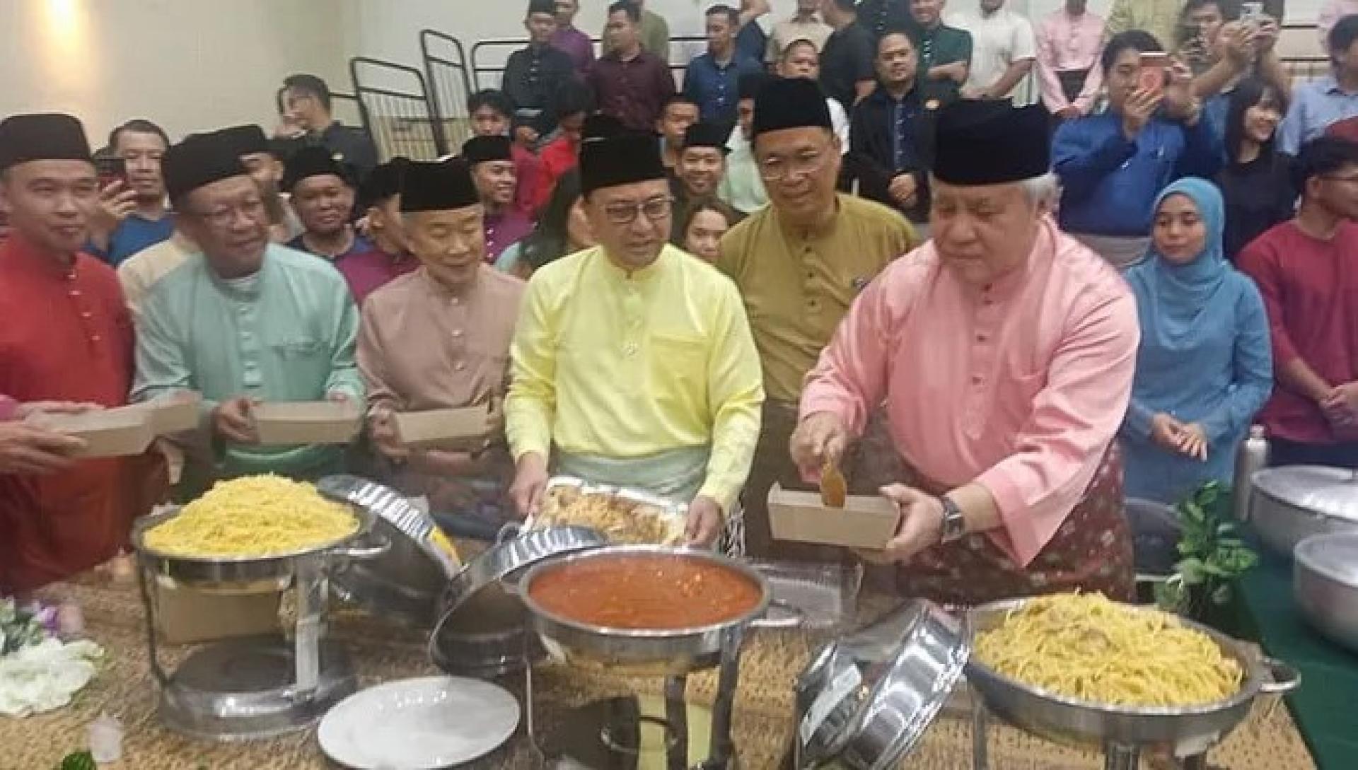 阿旺登雅（右）在2026年3月31日，于古晋Wisma Sabati出席森林局开斋节开放日活动时自取节日餐点。