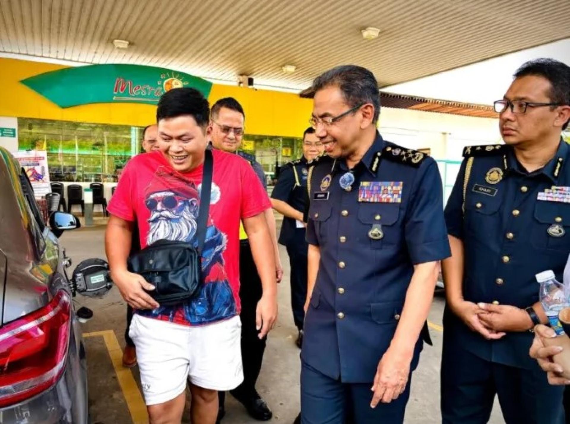 阿兹曼（中）于4月1日在国油碧湖加油站与一名准备按照新限量加油的司机交谈。