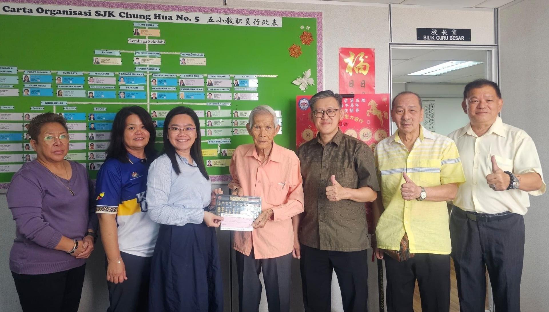 方由传（右4）在薛华东（右3）见证，移交其研发的“方氏数字转轮算盘”及捐献五小欲建礼堂一千令吉予五小校长郑茗月（左3）。左起为该校校友会财政朱缮霖，课外主任温惠妮，右起是陈中兴、孙守生。