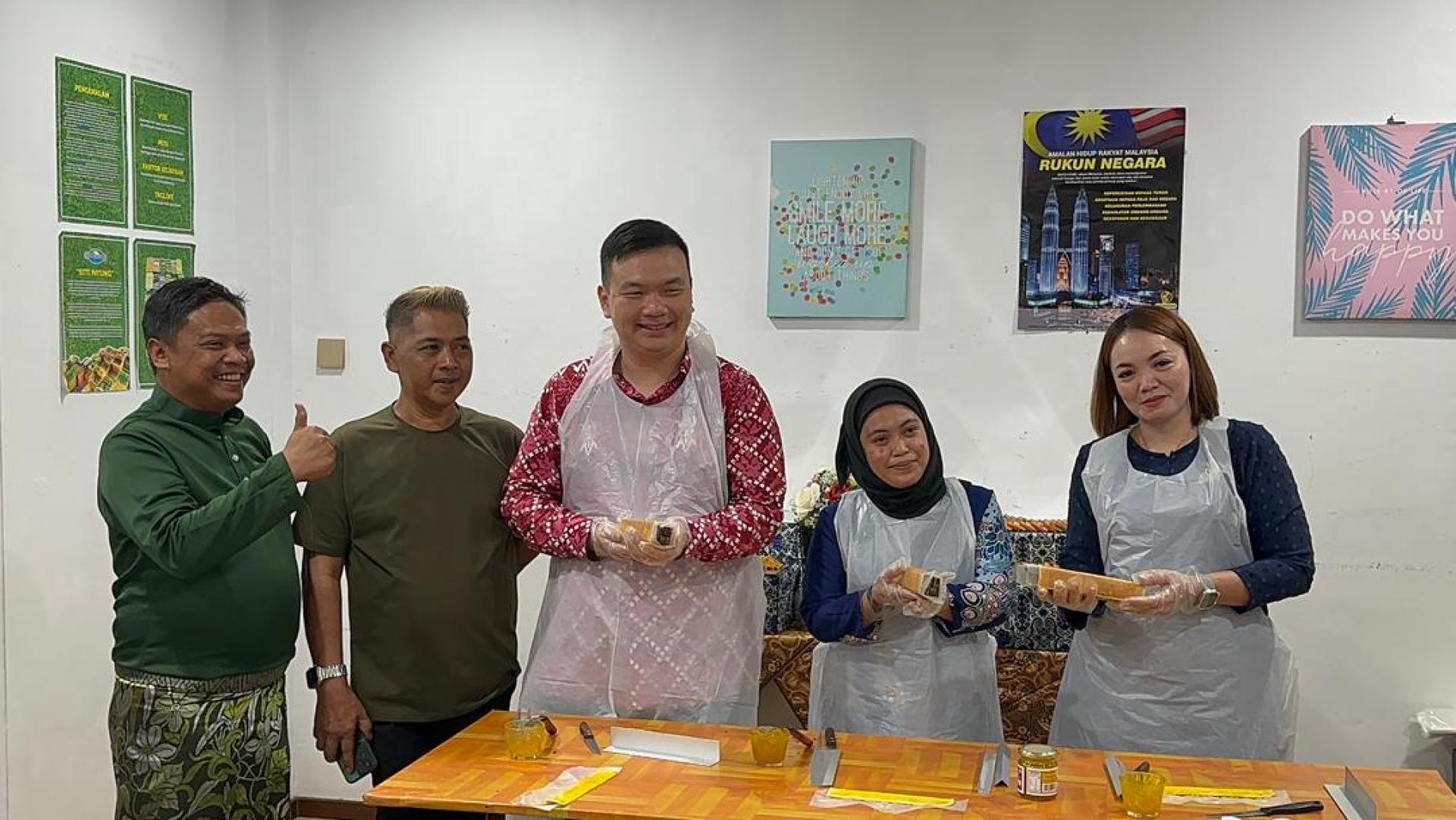 旅游、艺术及文化部副部长兼美里国会议员赵俊文（中）在砂拉越千层蛋糕馆尝试制作千层蛋糕。