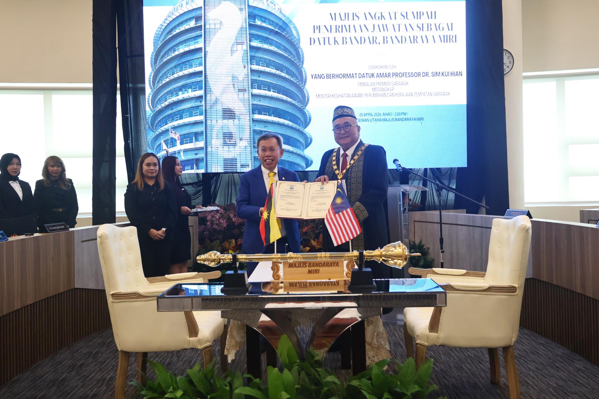 砂拉越副总理兼公共卫生、房屋及地方政府部长拿督阿玛沈桂贤（左）移交美里市长延任宣誓书给俞小珊。