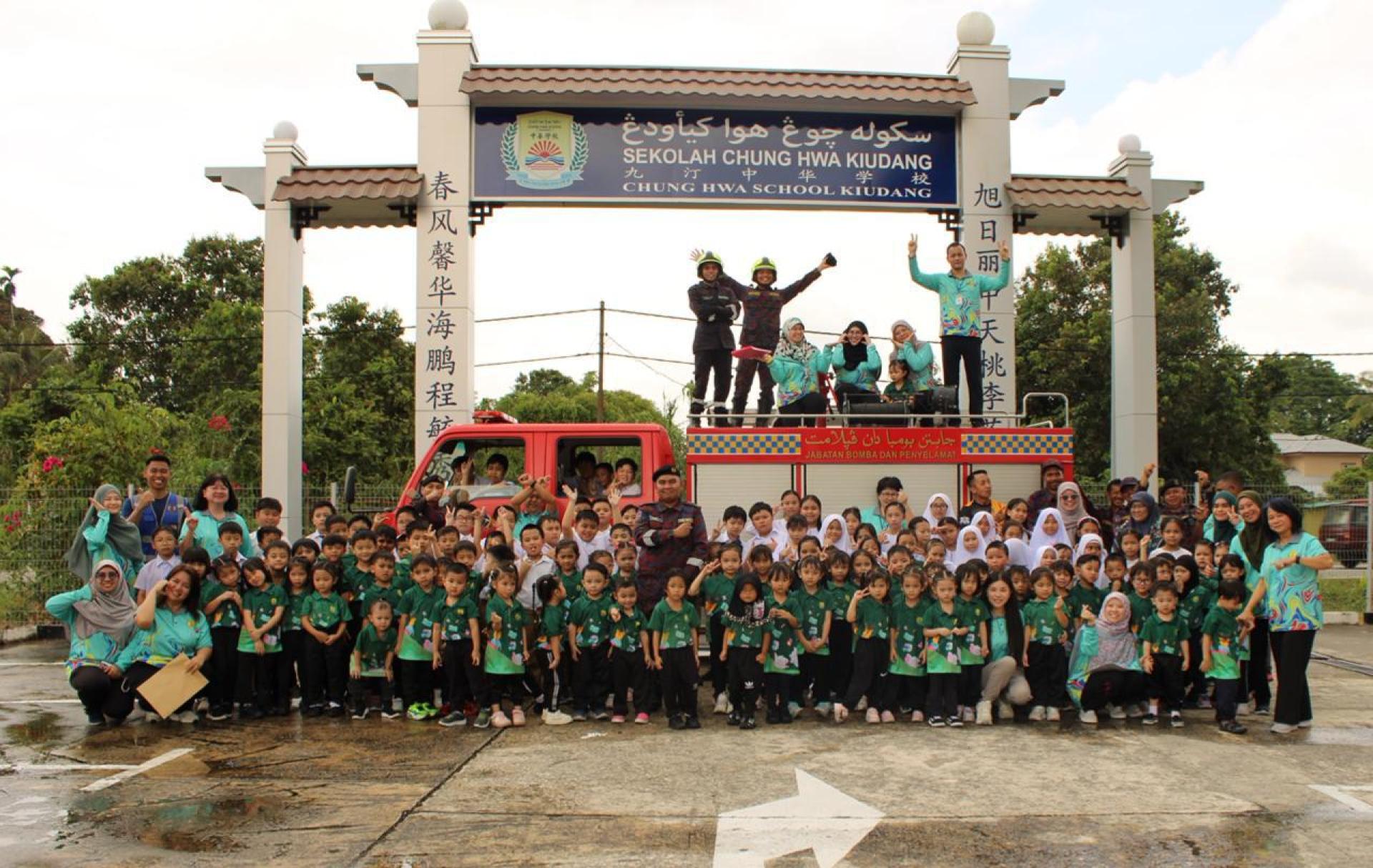 师生与消防局人员在校门前开心合影