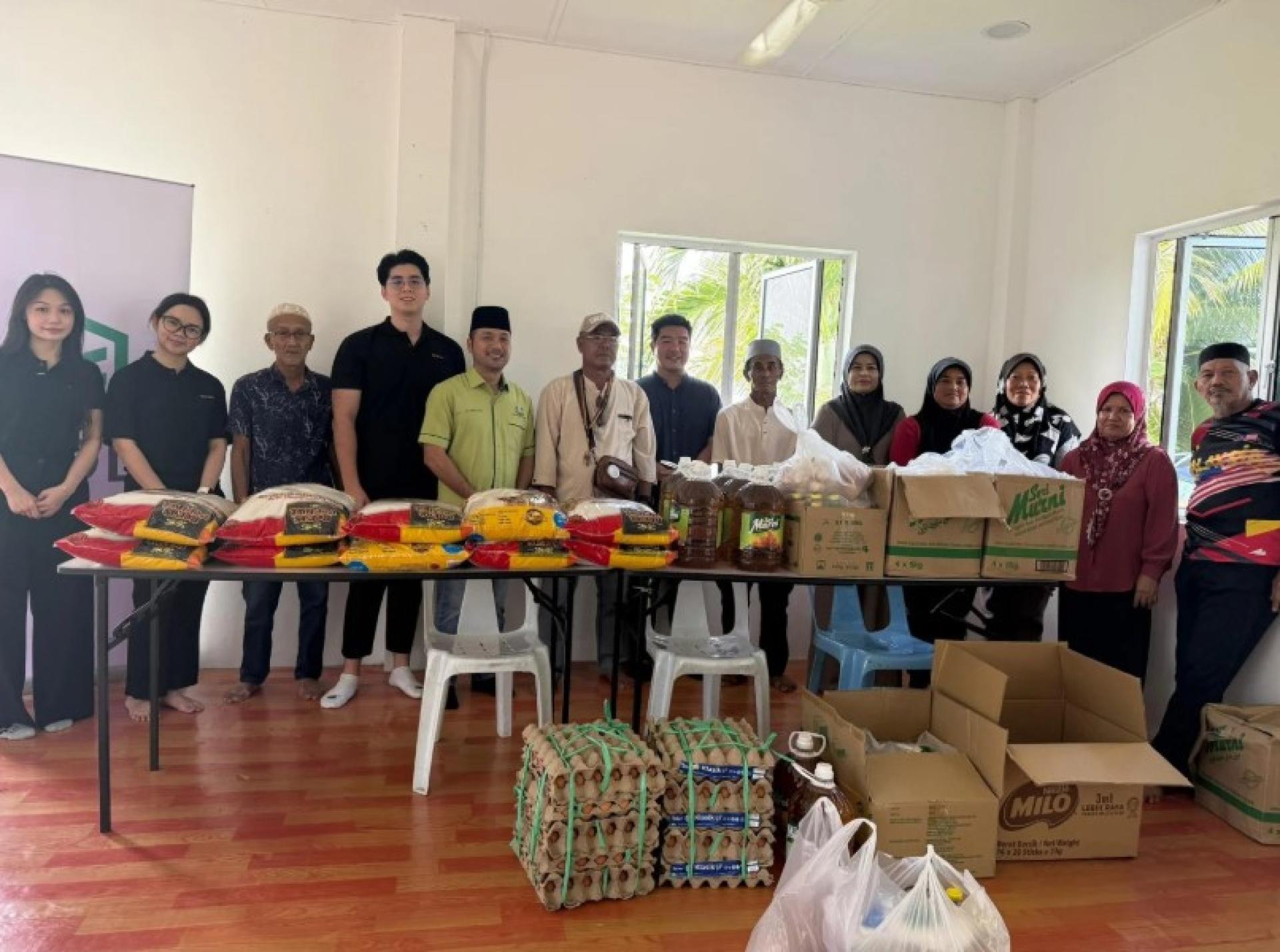 巴达旺市议会议员Mohamad Fauzi Ali（绿色衣着）与EXAL团队，将捐赠物资发放给受惠者。