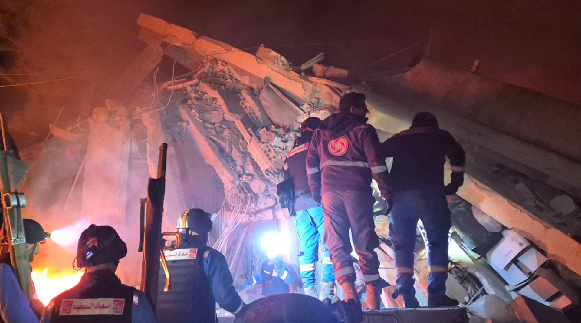 10日凌晨在黎巴嫩南部哈布什村，救援人员以色列空袭现场的废墟下进行搜寻。