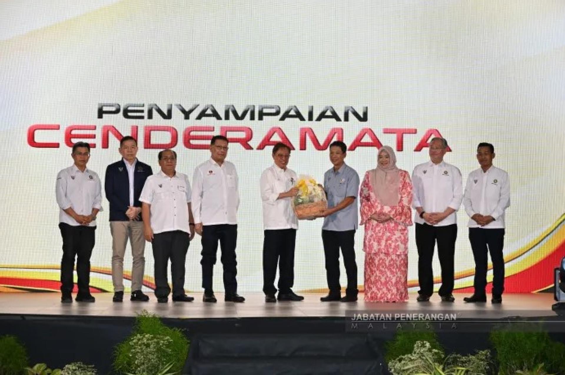 阿邦佐哈里（中）在斯里阿曼2026年龙芽区经济论坛上，从卡美里手中接过纪念品，众嘉宾在旁见证。