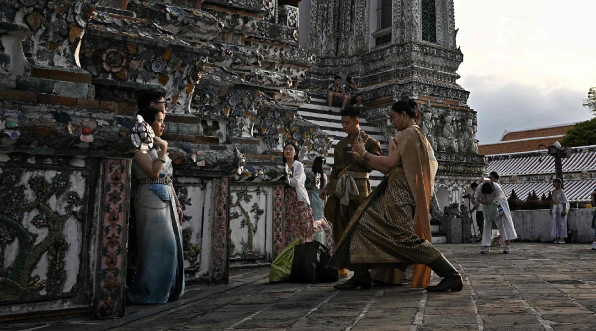 身着泰式传统服饰的游客在曼谷郑王庙拍照留念。