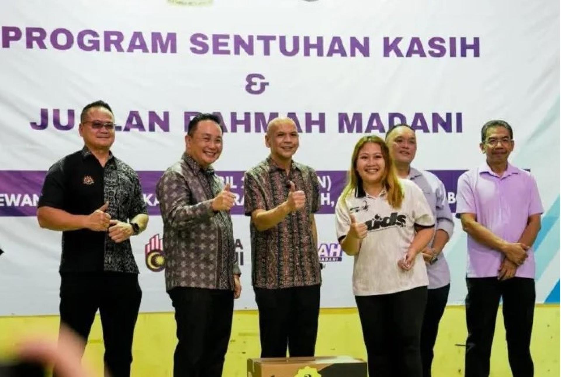 阿米占（左3）于2026年4月13日在婆罗洲高原举行的“Jualan Rahmah Madani Programme”（PJRM）活动中，与一名幸运抽奖得主合影。图中还可见（从左起）马修、威利、朱利斯及阿兹曼。