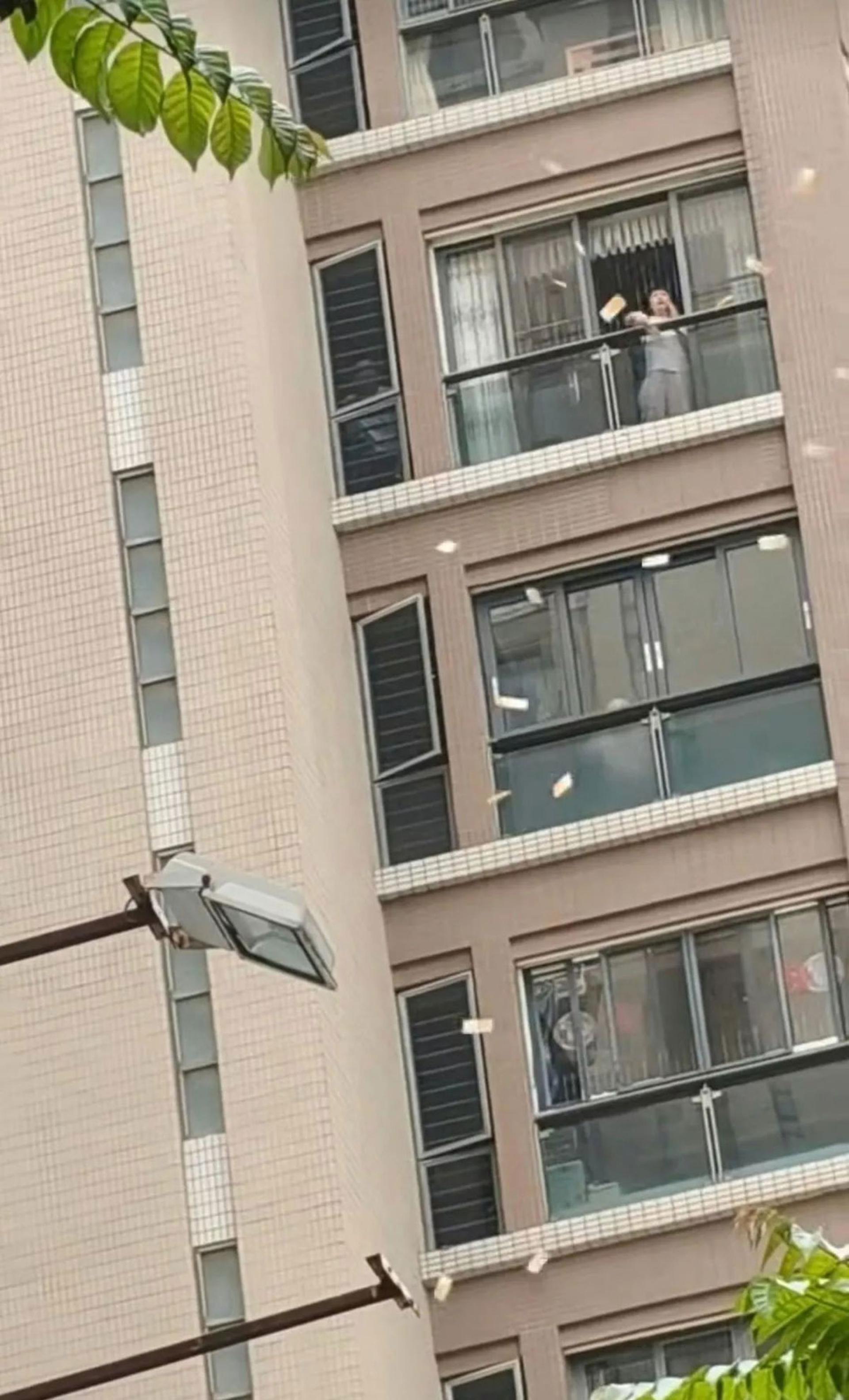广东汕头市一名大妈从高层单位露台将大叠面值1000元的港币“如天女散花”般抛向街外。