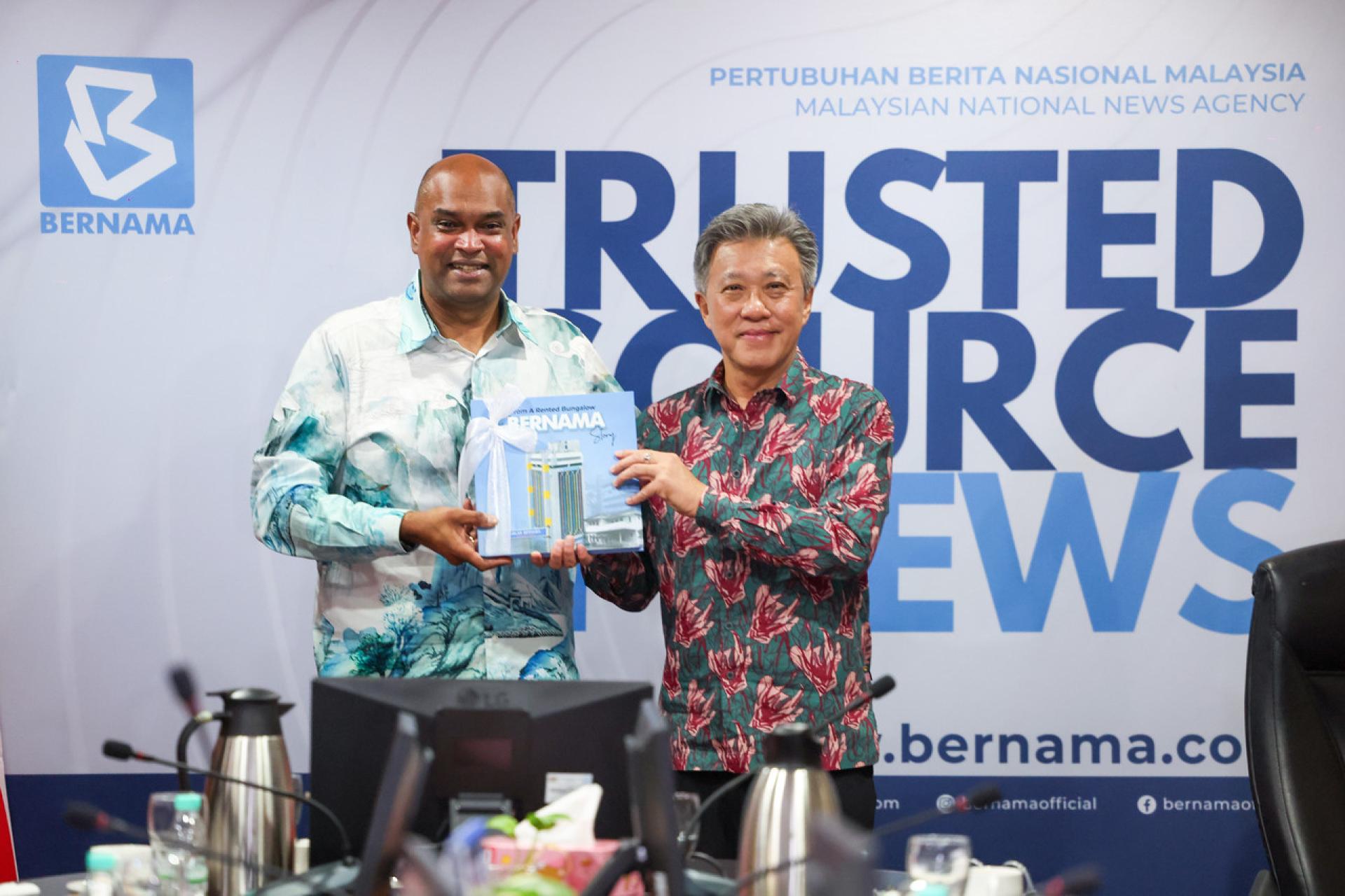 在出席“工作、薪资与未来”对话会后，主持人黄振威（右）赠送马新社书籍予拉马南（左）。