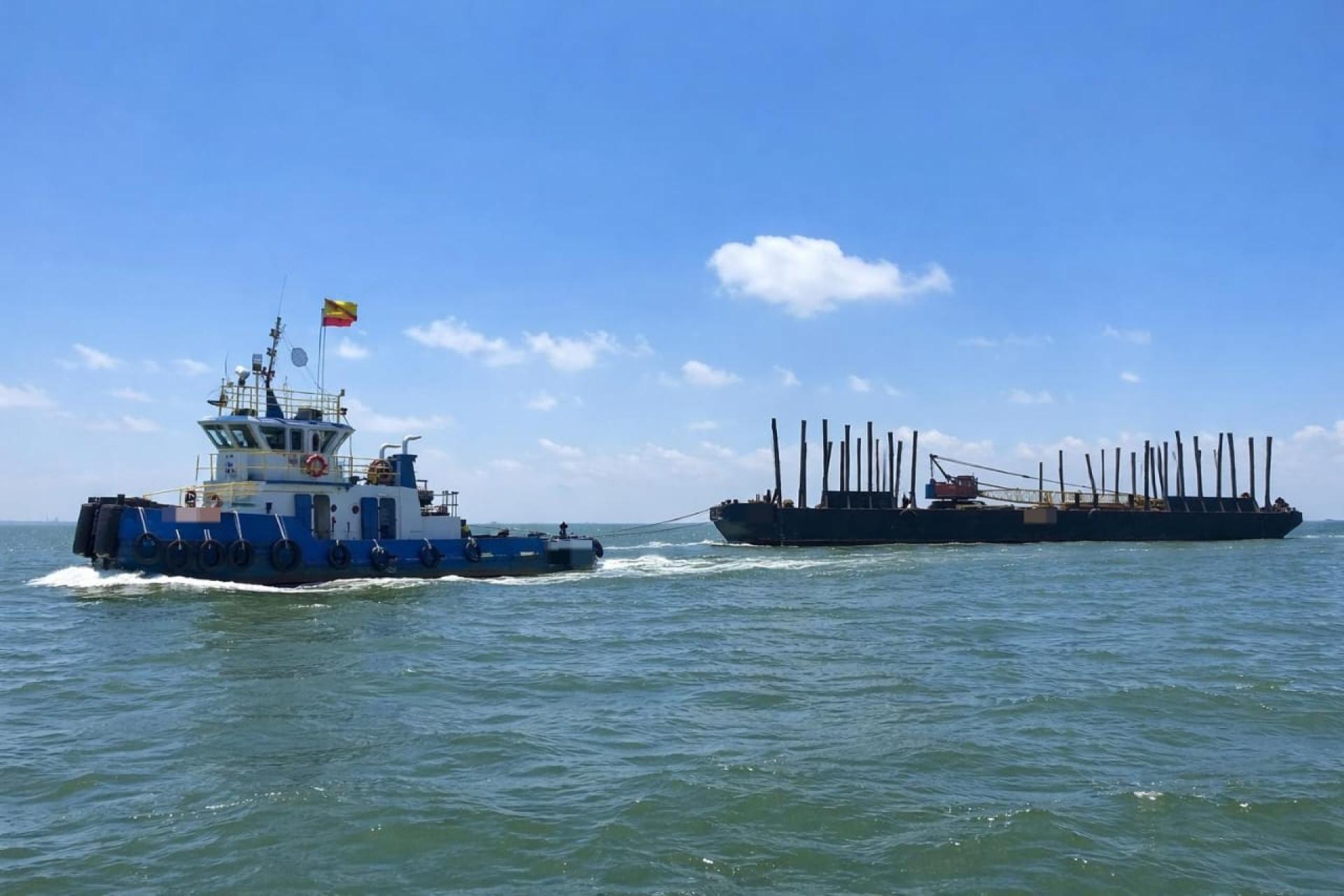 执法人员在海上拦截并检查涉案拖船及驳船。