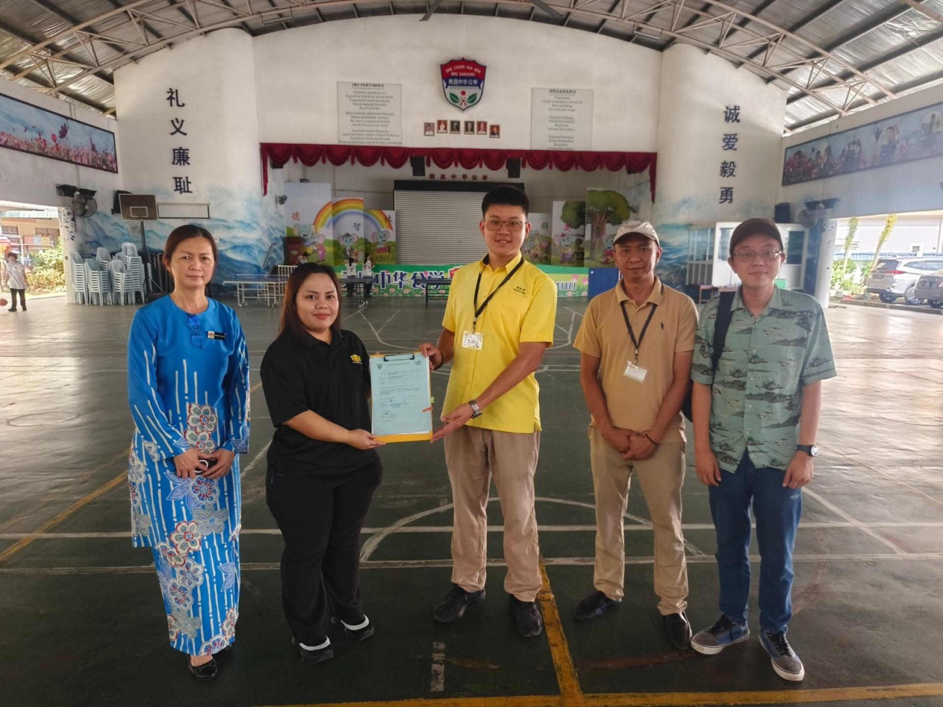 美里公共工程局官员代表移交已竣工的10万令吉工程报告予谢家洪（中），左1为美里中华公学首任校长黄玉霞。