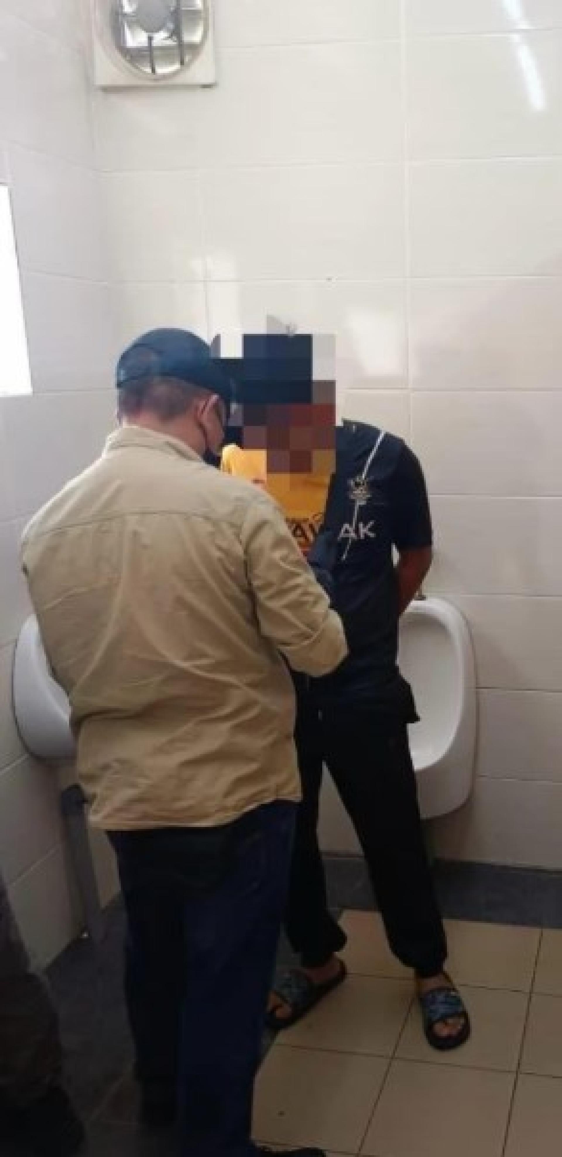 警方在加油站厕所内拘捕并检查嫌犯的情况。