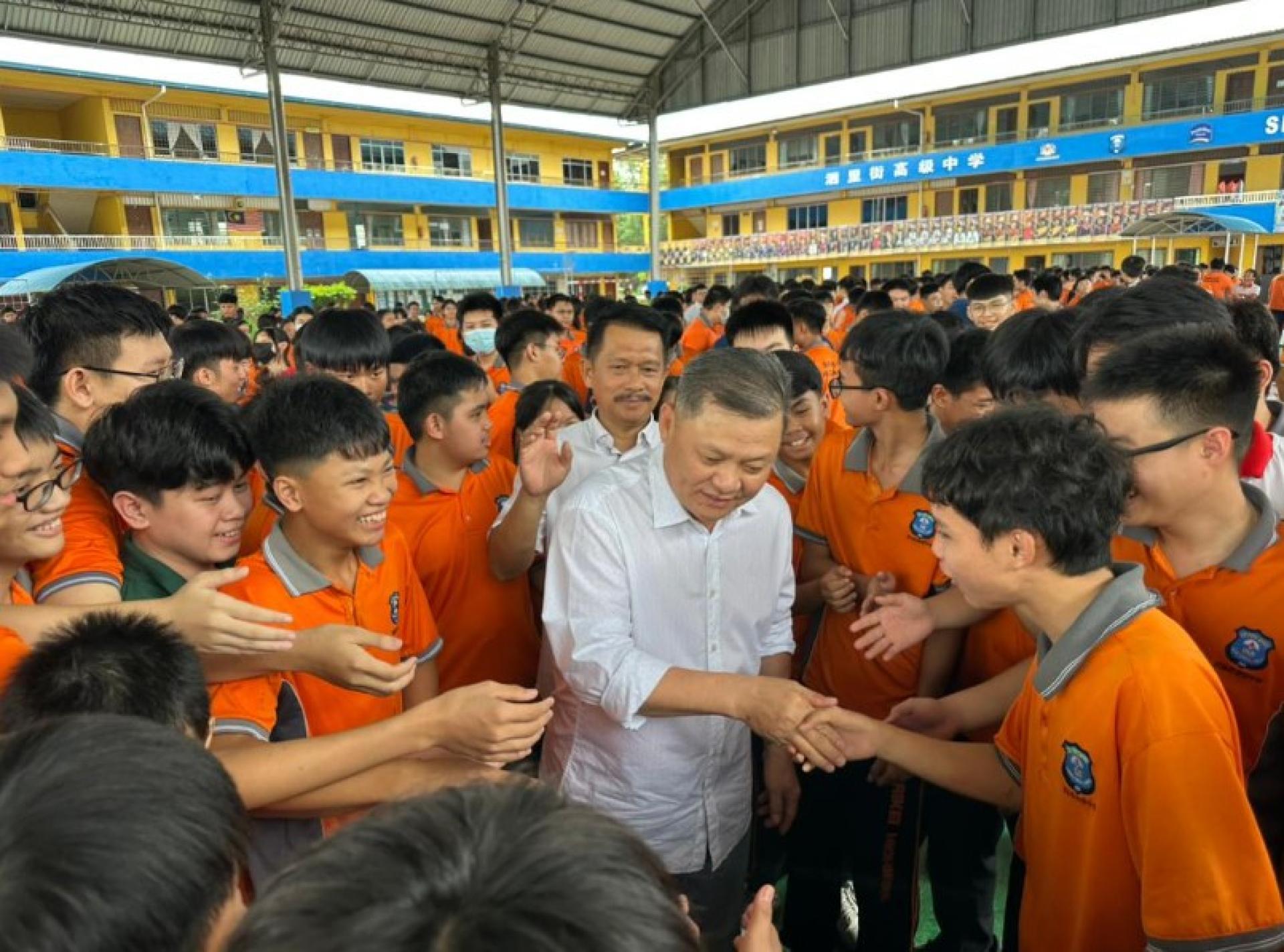 范长锡（中）在2026年校服与校鞋分发活动中与学生交流。