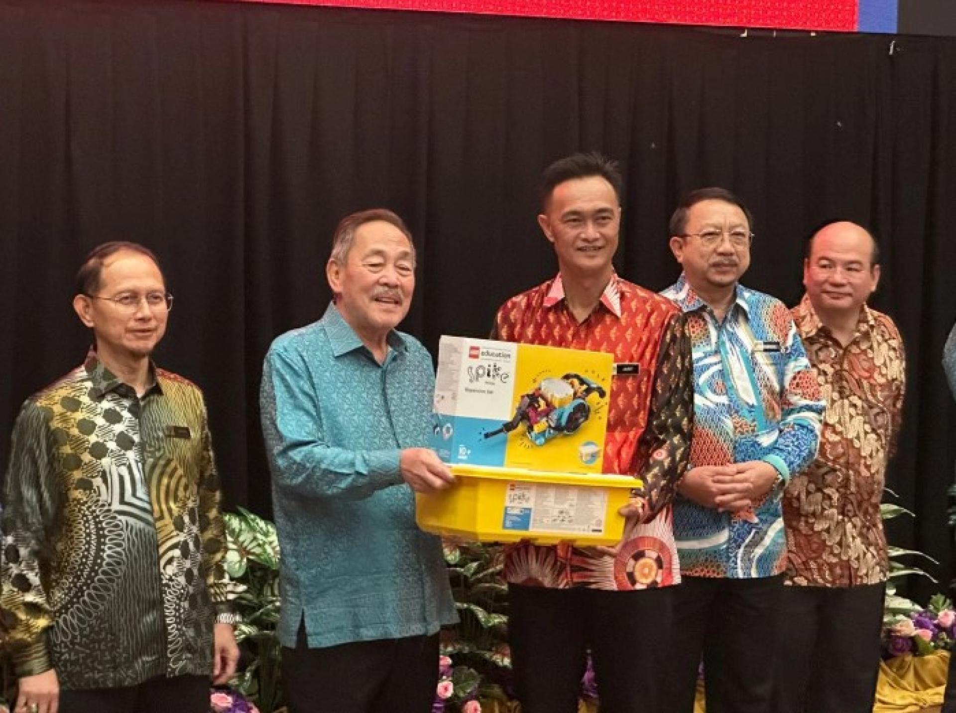 沙加向其中一所参加2026年全国机器人竞赛州级赛的学校代表移交机器人套件。