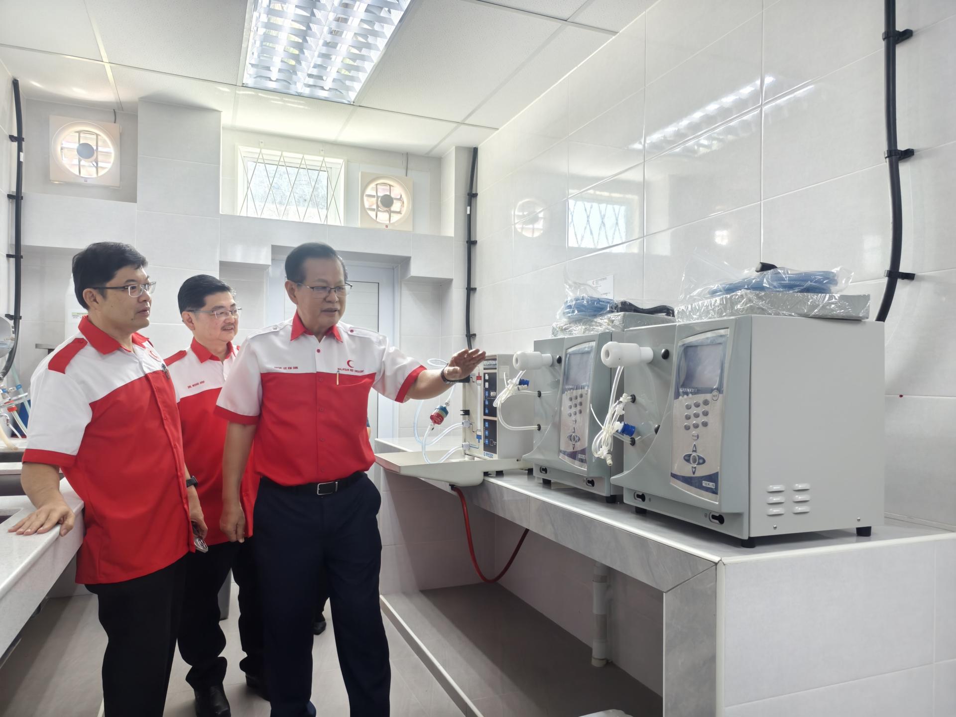 李景胜（右）与阿里夫医生（左2）及黄修儒医生（左）等巡视透析器再处理机与洗瓶机室。