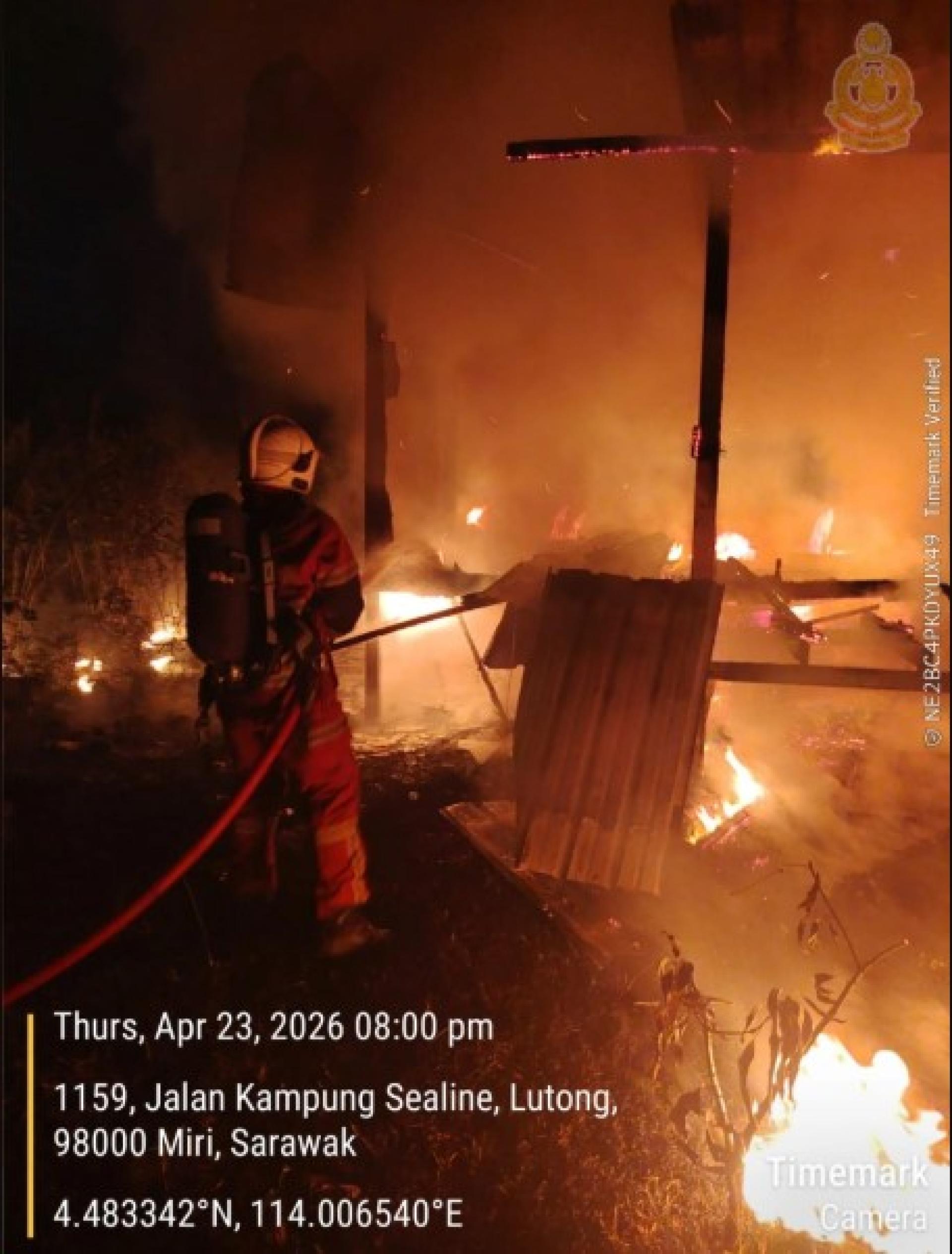 一名消防员正在喷水灭火，消防队正全力控制火势。