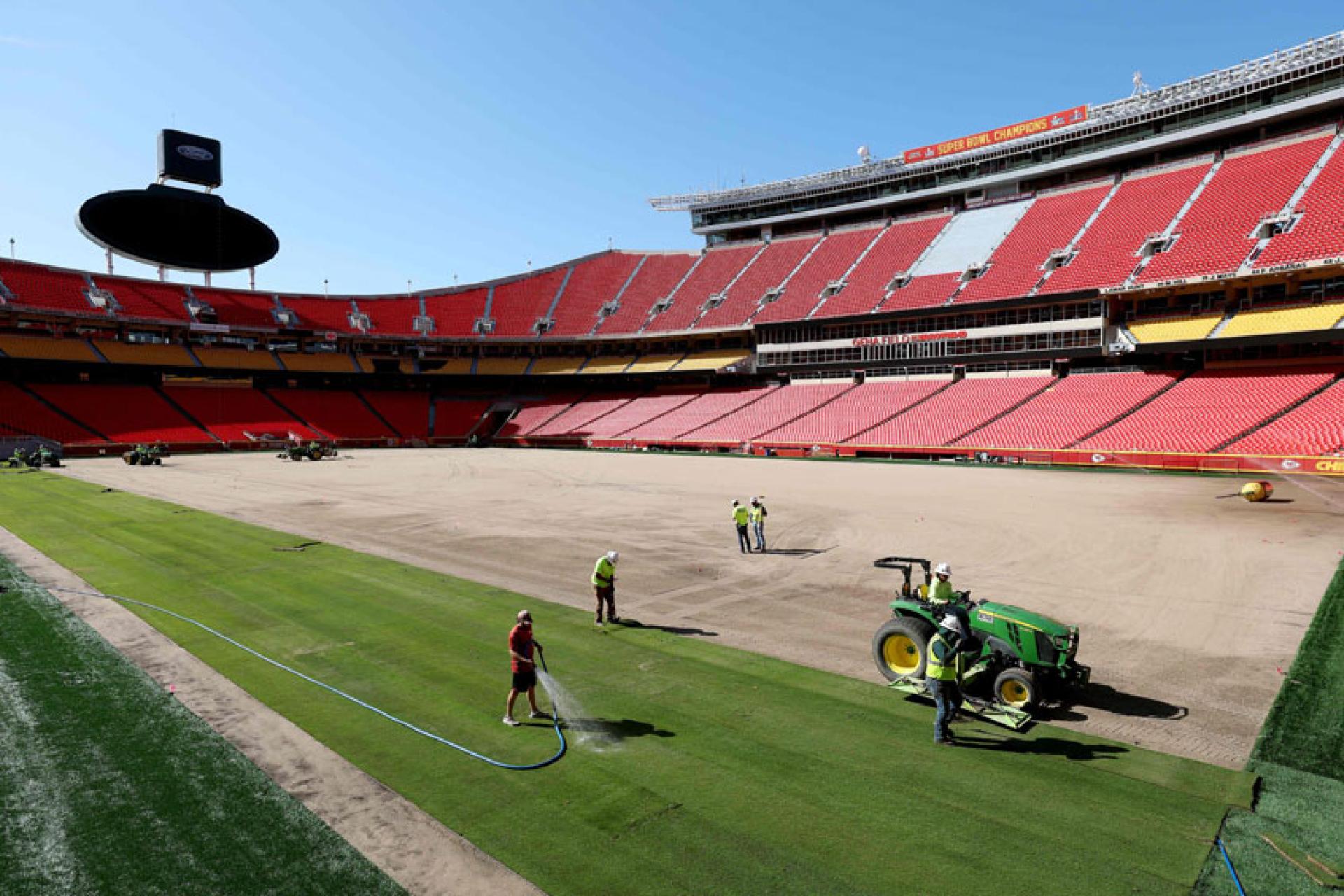 一群工人在密苏里州堪萨斯城体育场为世界杯场地铺设草皮。