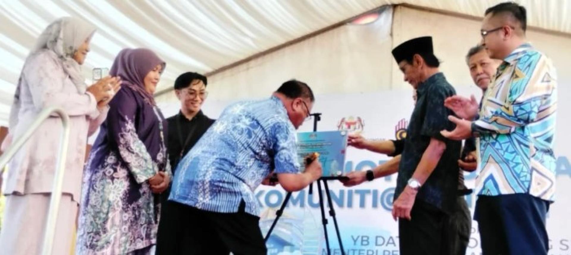 张庆信于周五在瓜拉达岛努尔伊曼村“昌明亲乡计划（KAM）”移交仪式上签署纪念牌。