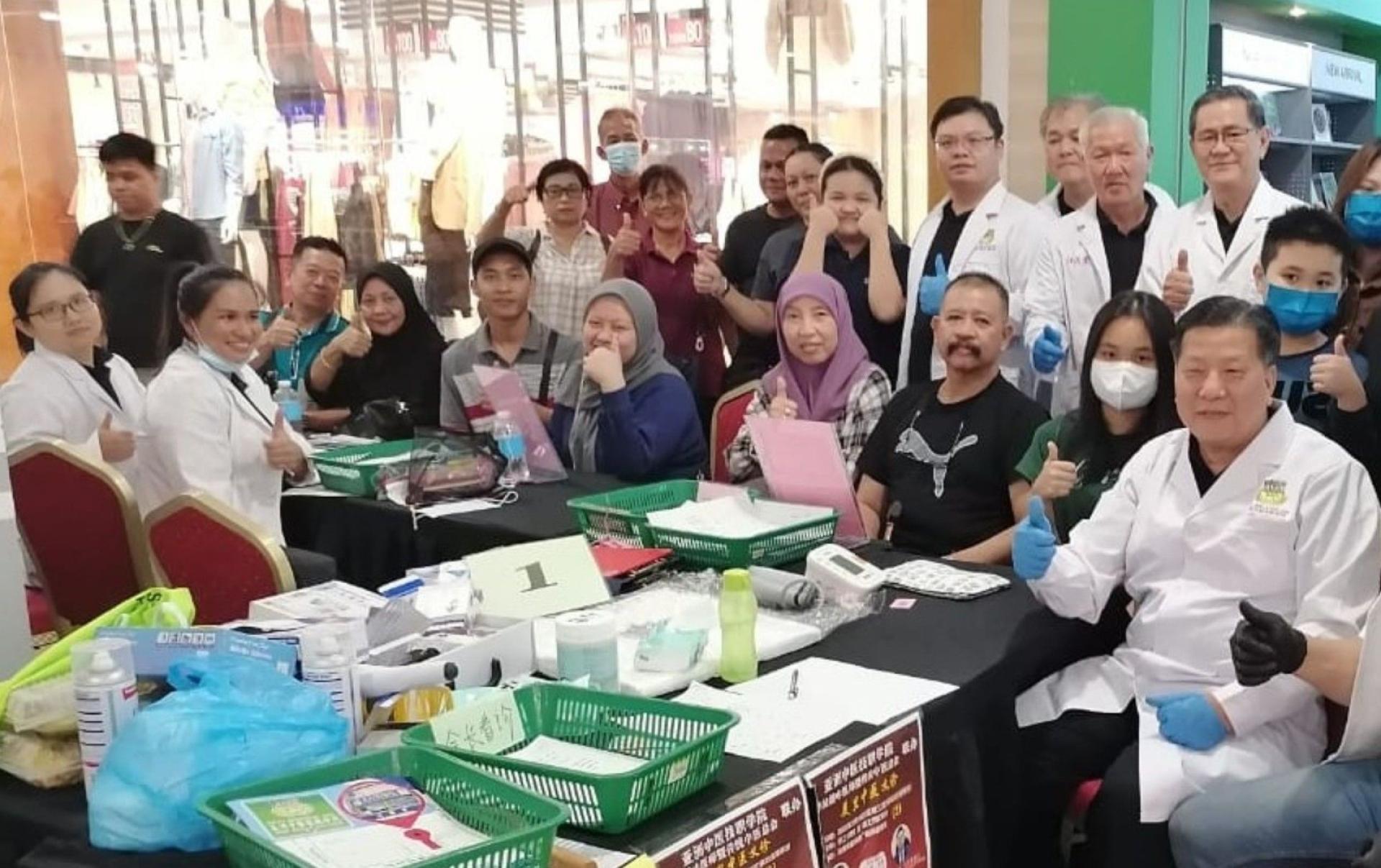砂医总会长江宗兴（前排右）领导中医义诊团队不分种族进行服务。