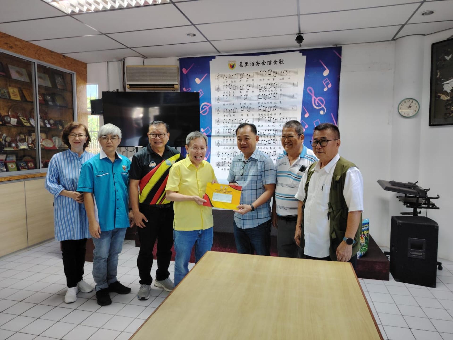 拿督阿玛沈桂贤（左4）移交拨款予杨洪林（右3）时摄。