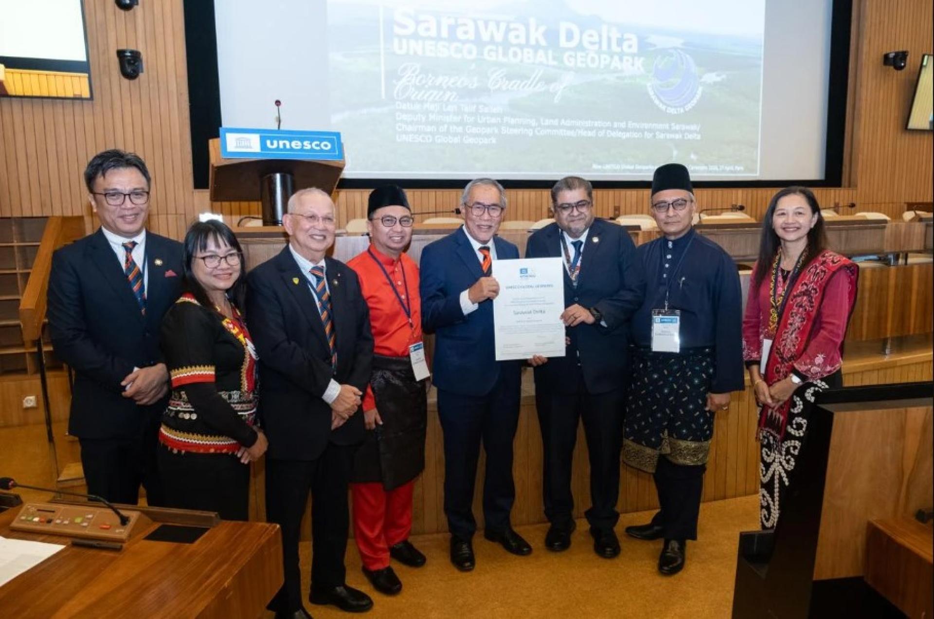 拿督连达立（左5）与砂拉越代表团合影时展示认证证书。