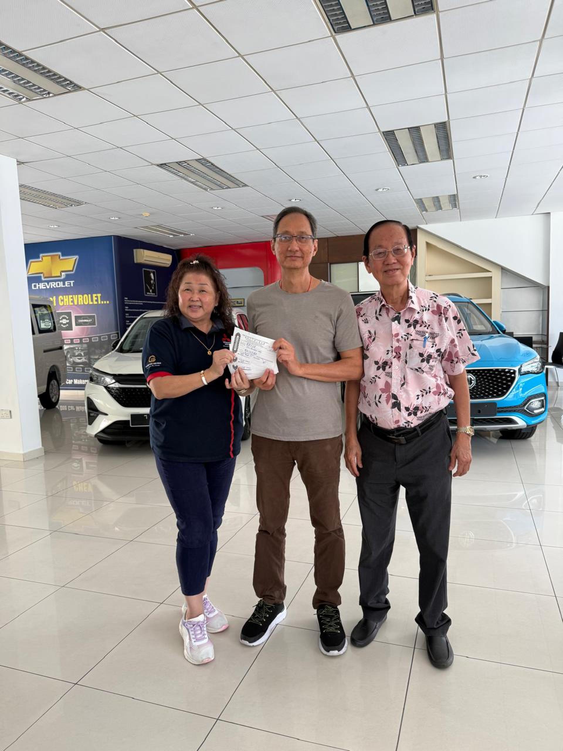 黄竞兴（中）代表家族成员将款项移交予慈善会理事沈秋香及郑炳光。