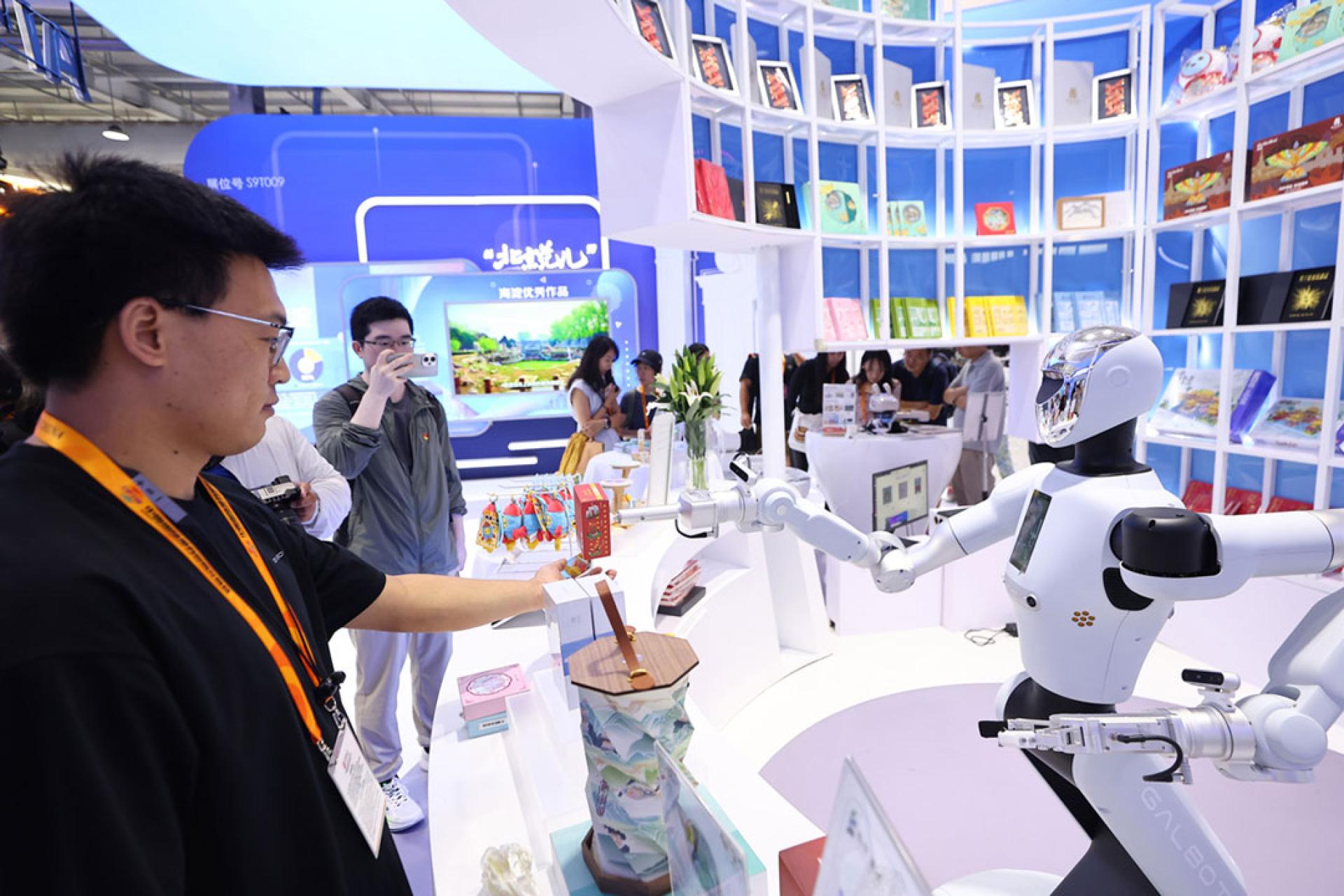 在2025年服贸会文旅服务专题展上，机械人将文创产品送到参观者手中。