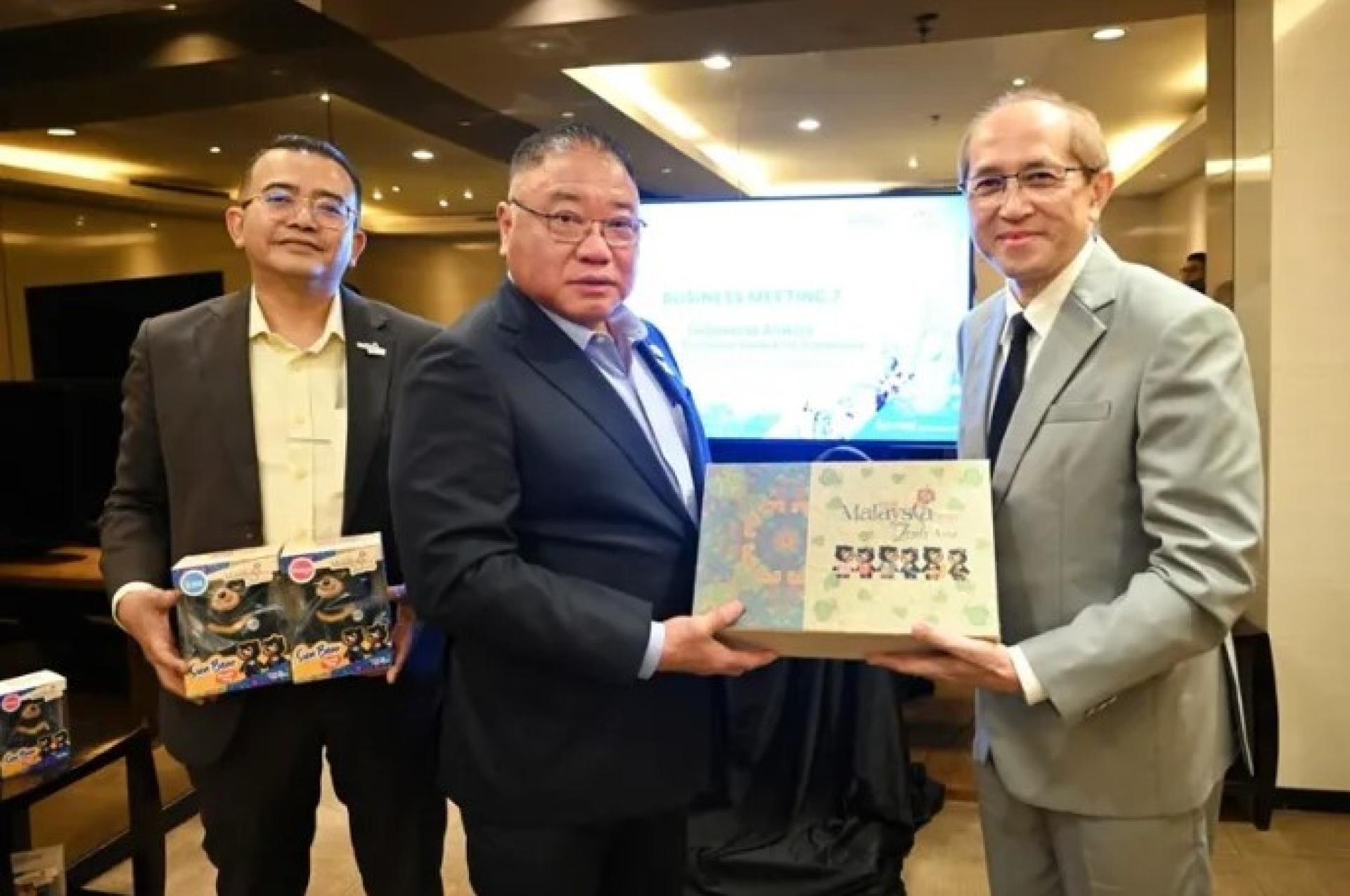 张庆信（中）日前在会面中向亚航印尼代表赠送纪念品。