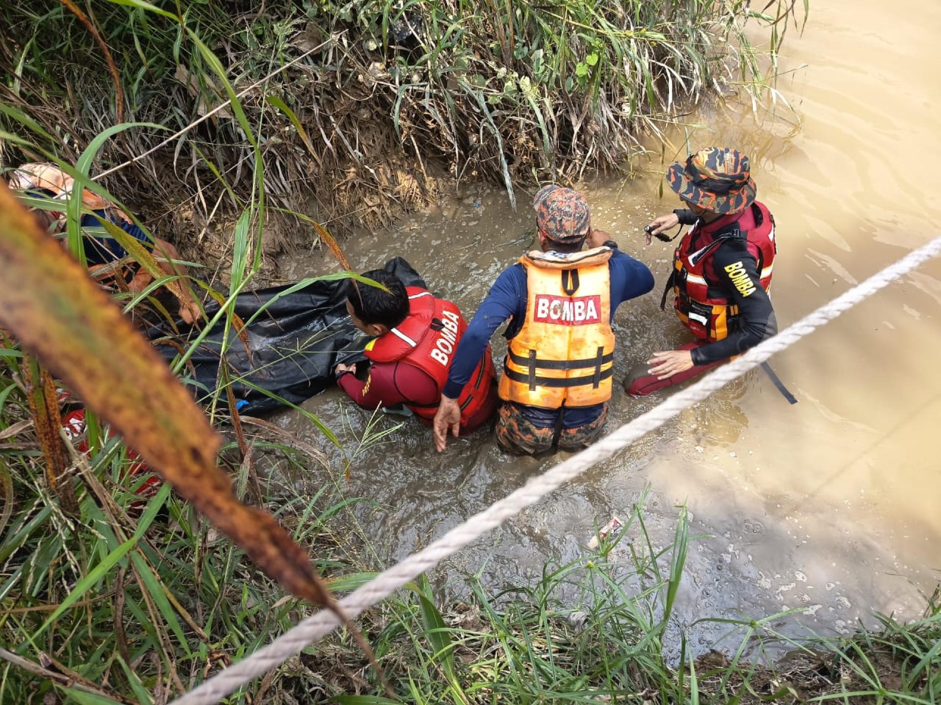消拯员从河流把男童遗体抬上岸。