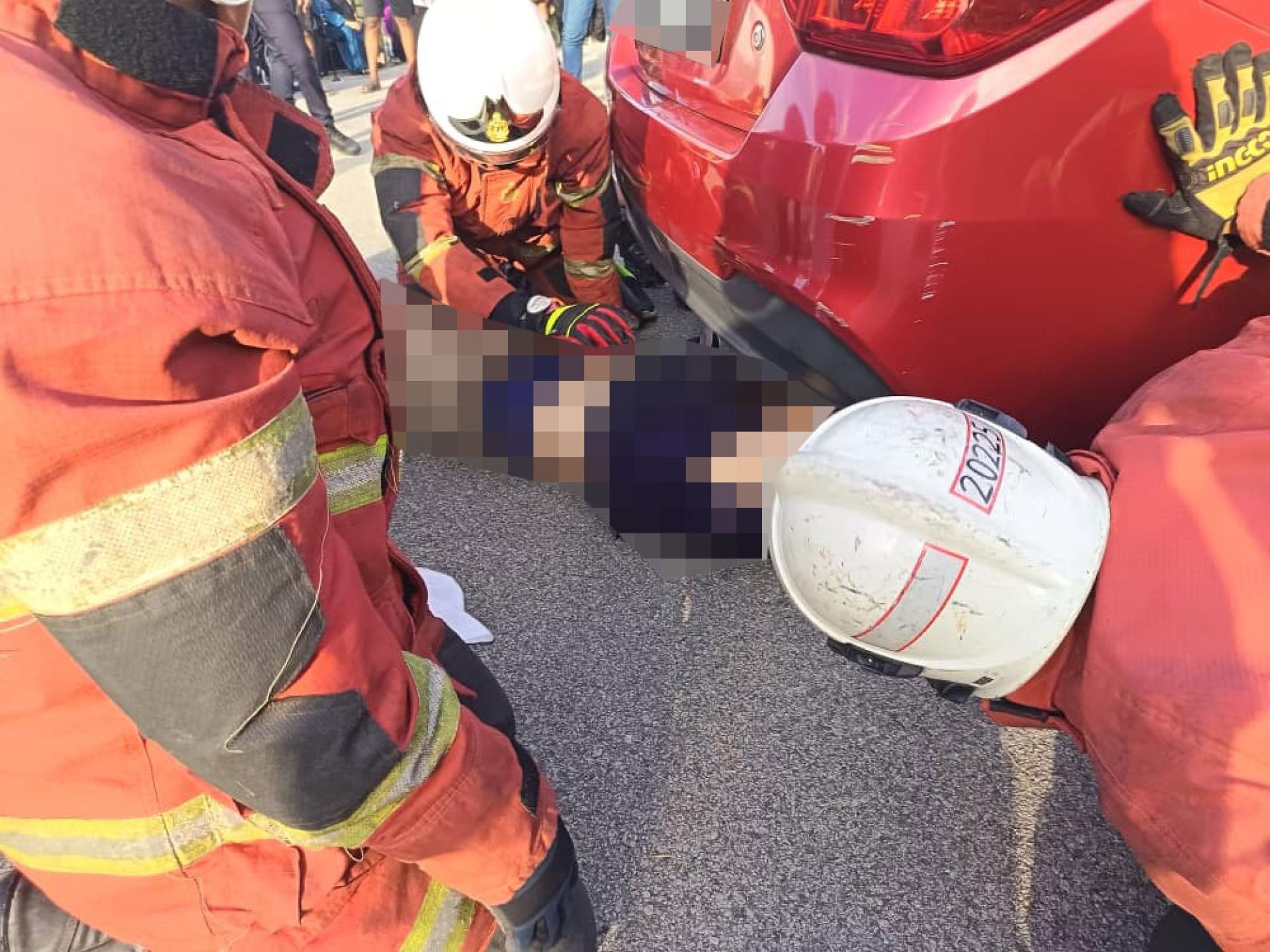 消拯员合力将被卷入车底的死者移出来。