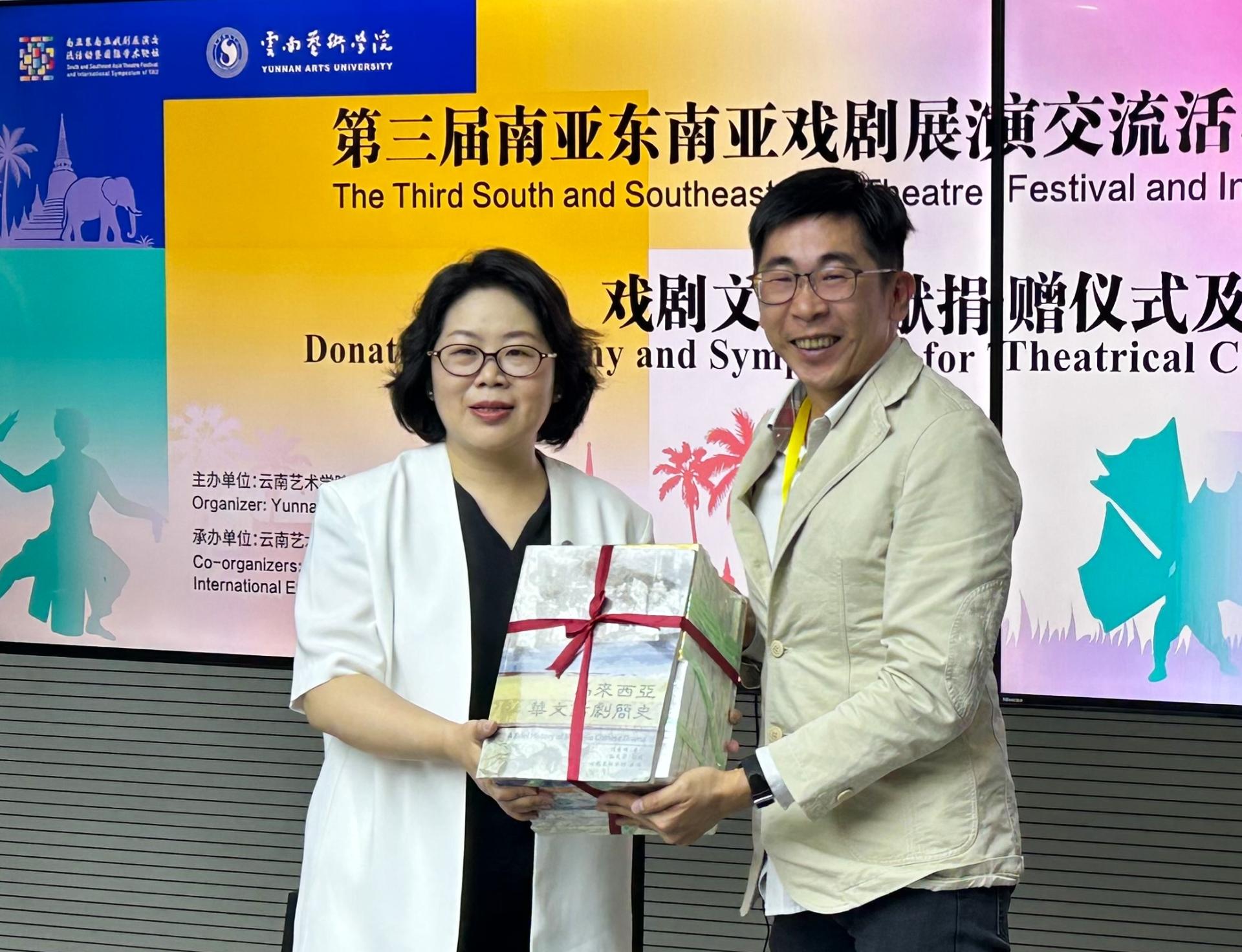 沈国明（右）代表心向太阳剧坊捐赠“马来西亚华文戏剧丛书”一套29册予云南艺术学院典藏，由杨军（左）代表接领。