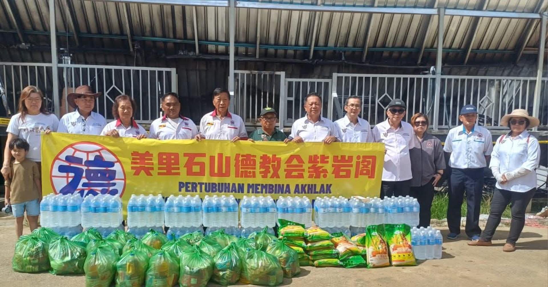 石山德教会紫岩阁福利组及理事，移交赈款及生活物资予尼尔逊宁甘长屋灾民，并由屋长尼尔逊宁甘（右7）接收，苏必士华人社区领袖在场见证。右6为紫岩阁阁长本固鲁贝冠鹏。