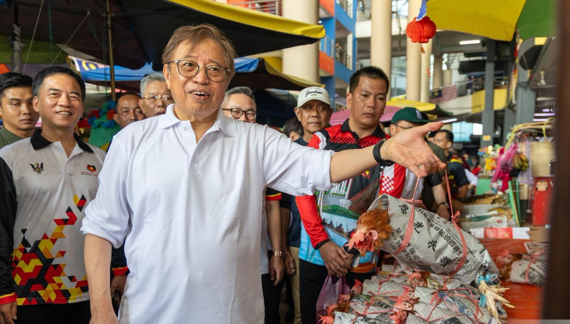 总理阿邦佐哈里在诗巫中央市场手持特色“纸包鸡”。